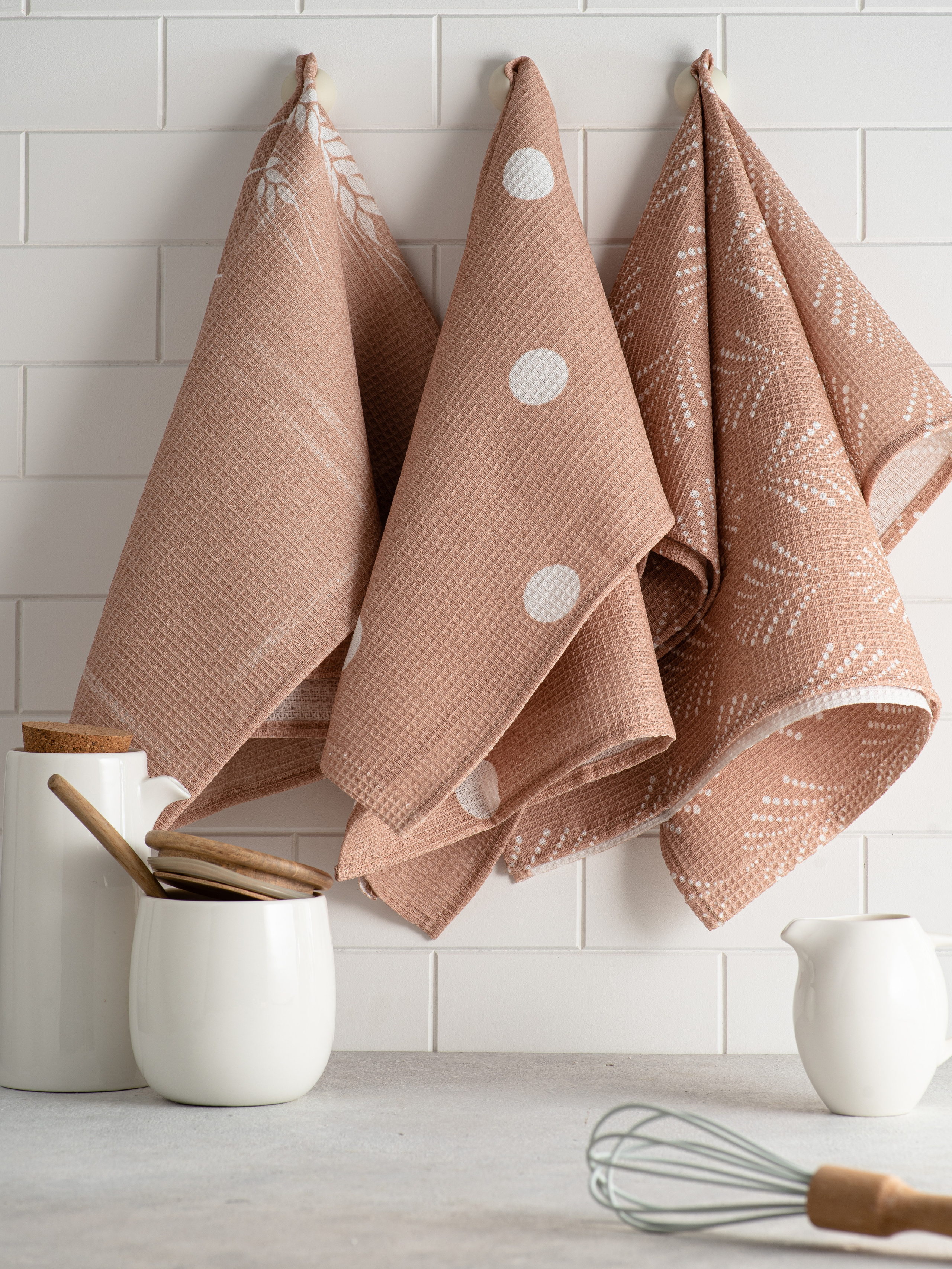 Коричневые полотенца на крючках на белой кухне