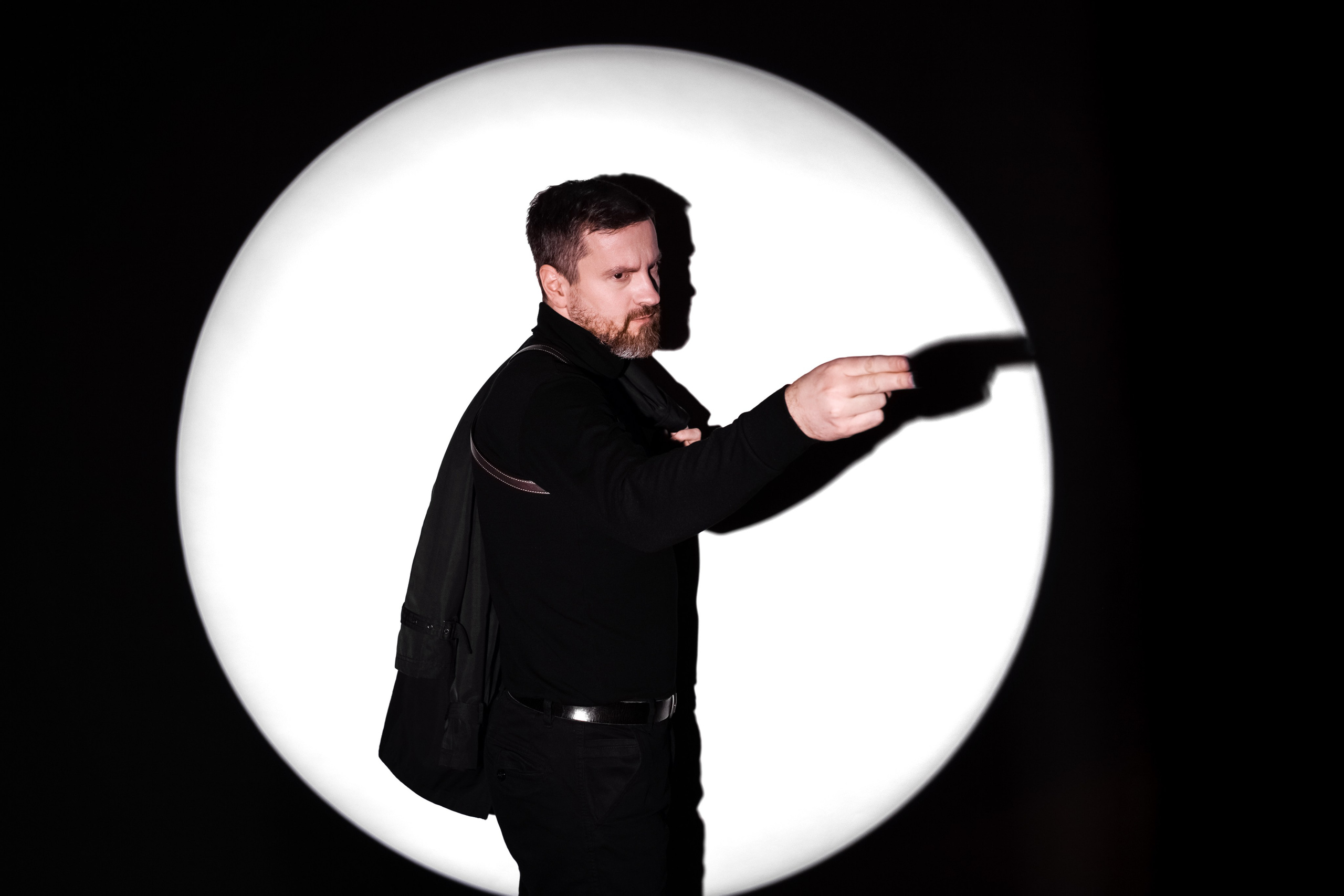 Мужчина с бородой в черном в белом круге света