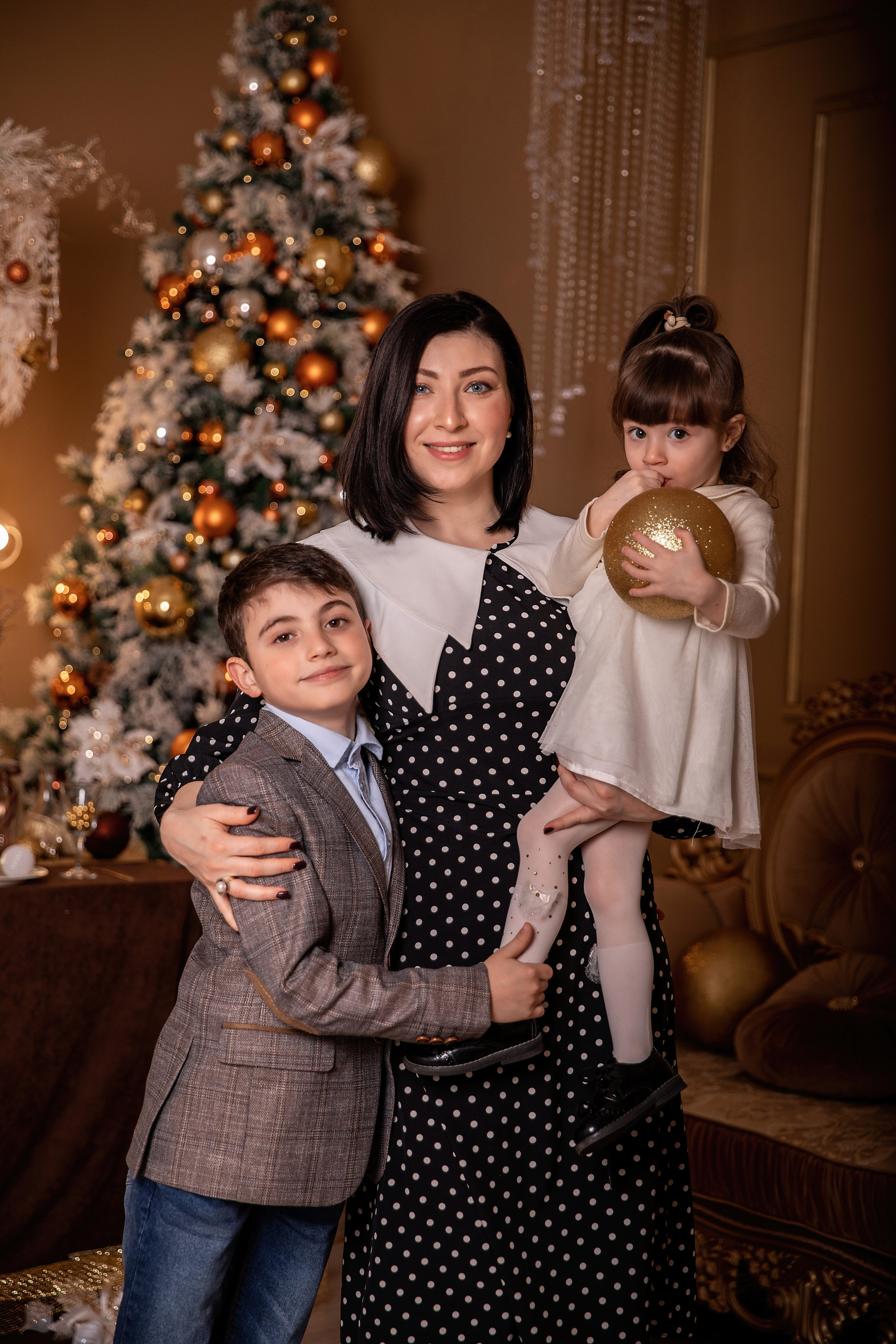 Семейная новогодняя фотосессия мамы с детьми в уютной праздничной студии у елки