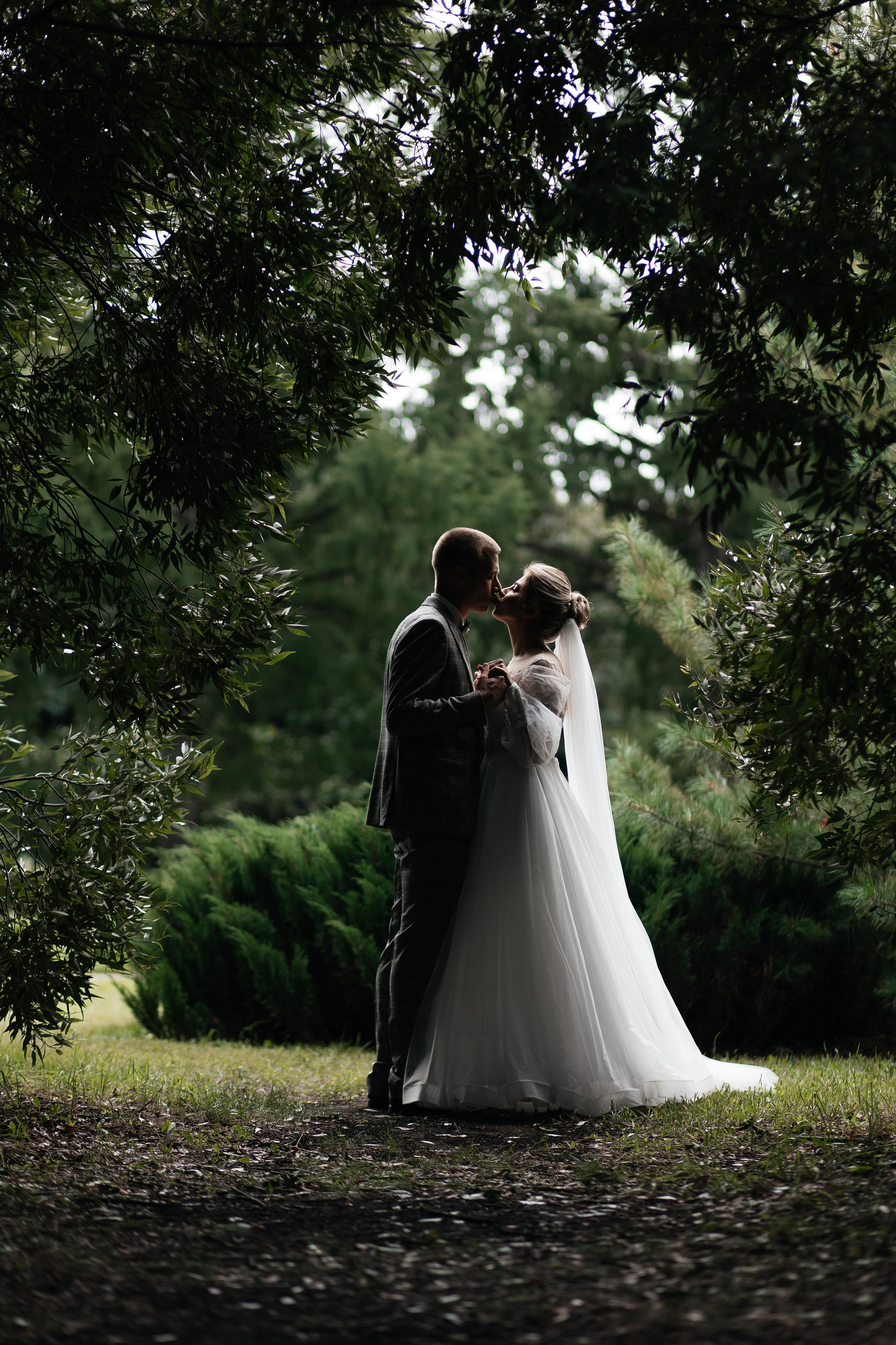 Жених и невеста обнимаются под цветочной аркой во время церемонии бракосочетания в Москве, свадебное фото. Молодожены на фоне московских достопримечательностей, свадебная фотосессия в Москве, профессиональный свадебный фотограф