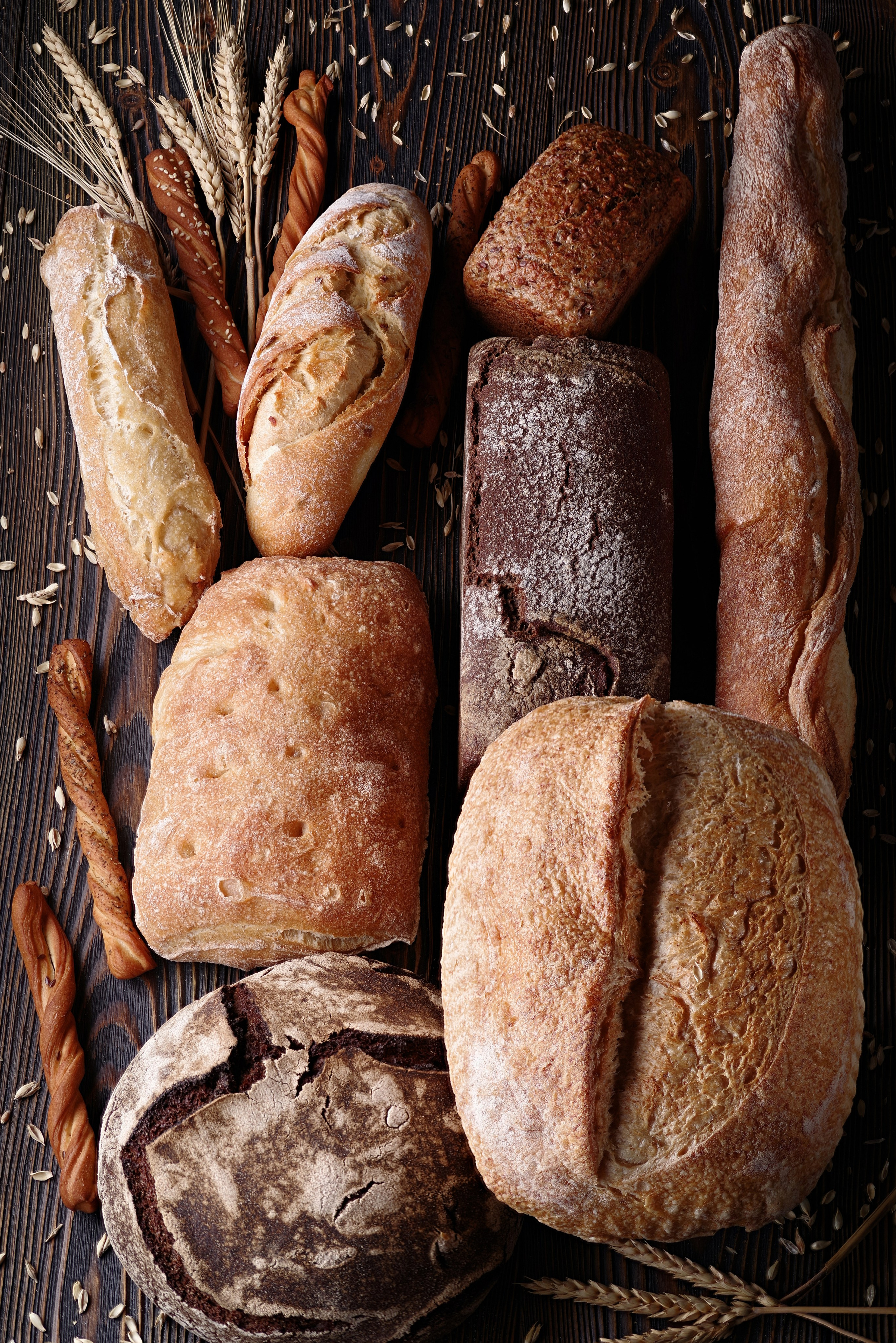 Разные виды хлеба на деревянном столе с колосьями пшеницы