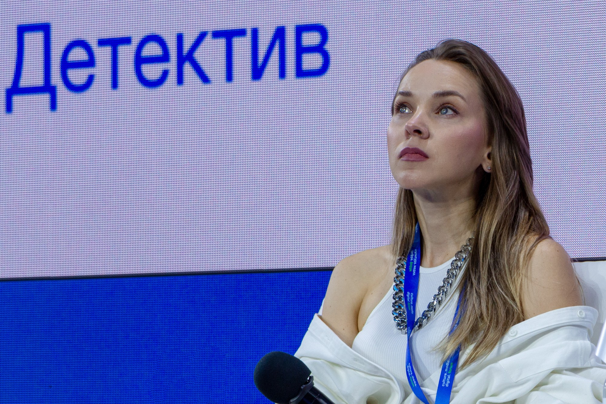Фотосъемка спикеров продюсер Олеся Грибок на фоне экрана с надписью Детектив во время выступления на международной конференции