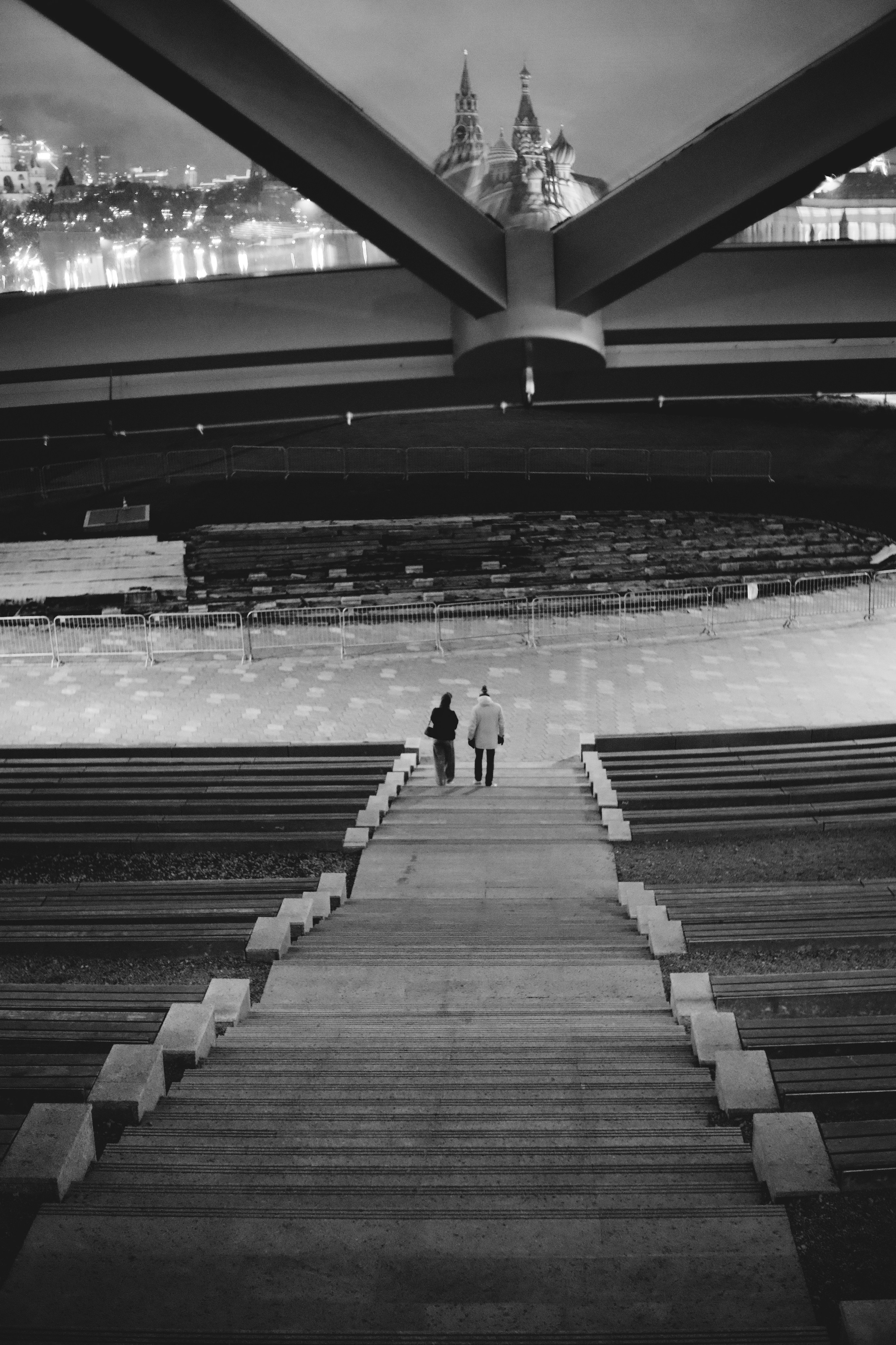 два человека, спускающихся по лестнице крыши концертного зала в парке Зарядье в Москве на фоне Кремля