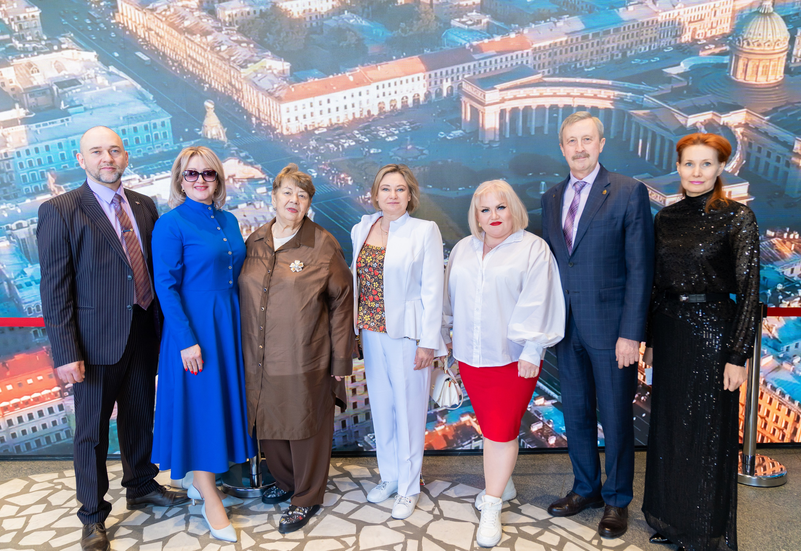 Участники торжества в честь Дня местного самоуправления позируют на фоне большой панорамы Санкт-Петербурга. Групповой портрет. Фотография Евгения Мальцева.