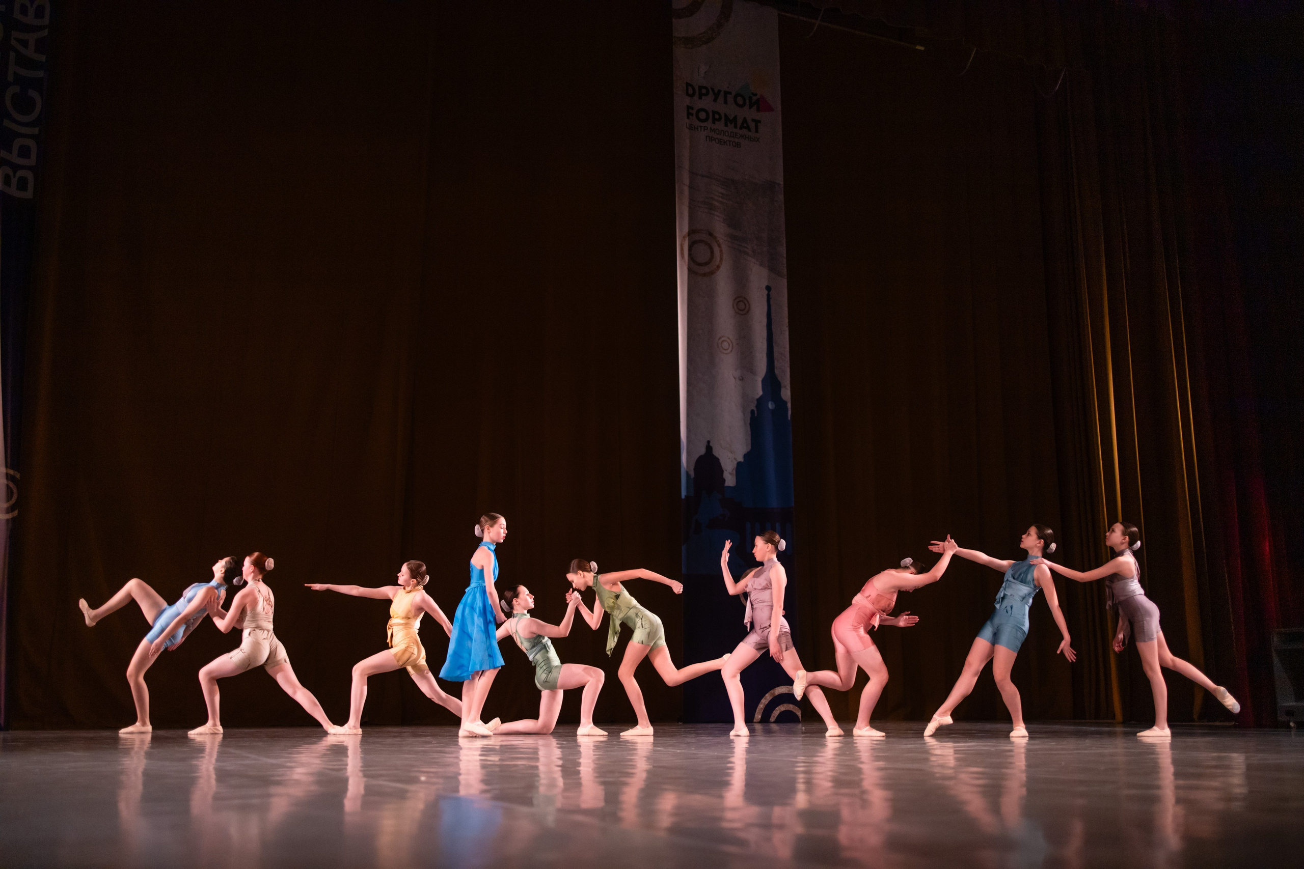 Общий план, где танцоры создают динамичную «живую картину» на сцене.