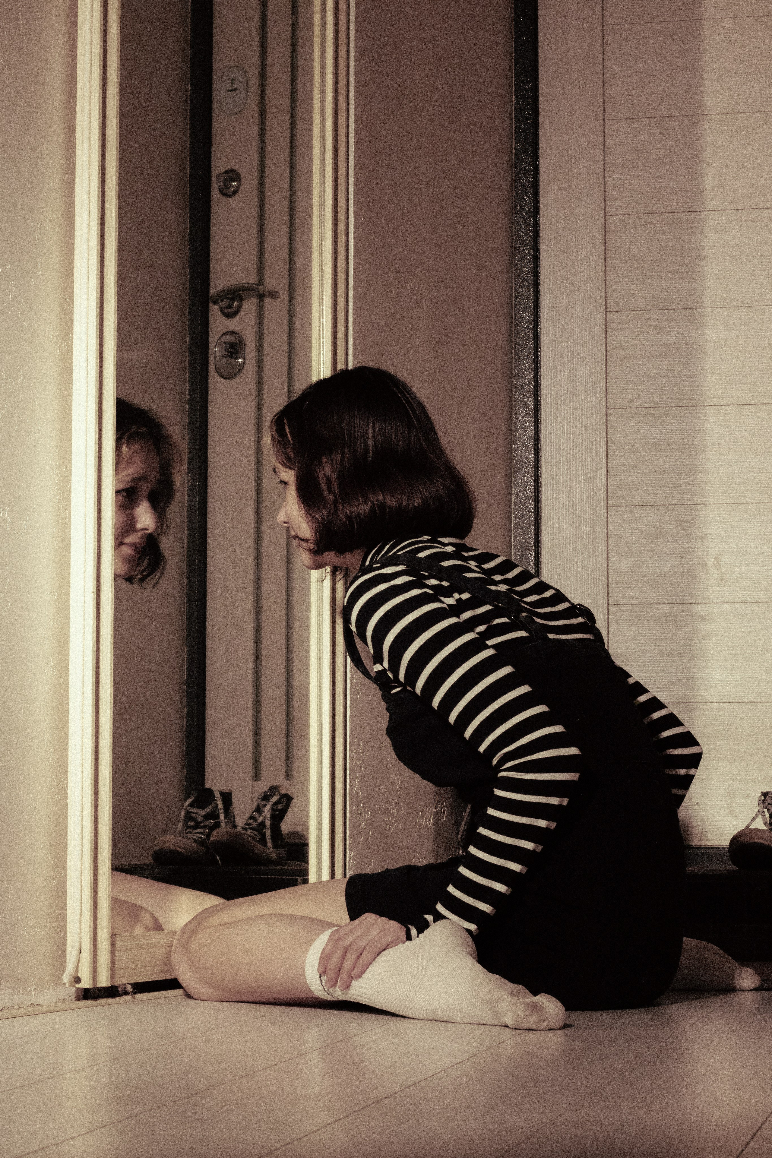 Девушка смотрит в зеркало, в отражении — лицо сестры, как боль, которую не отпустить.
