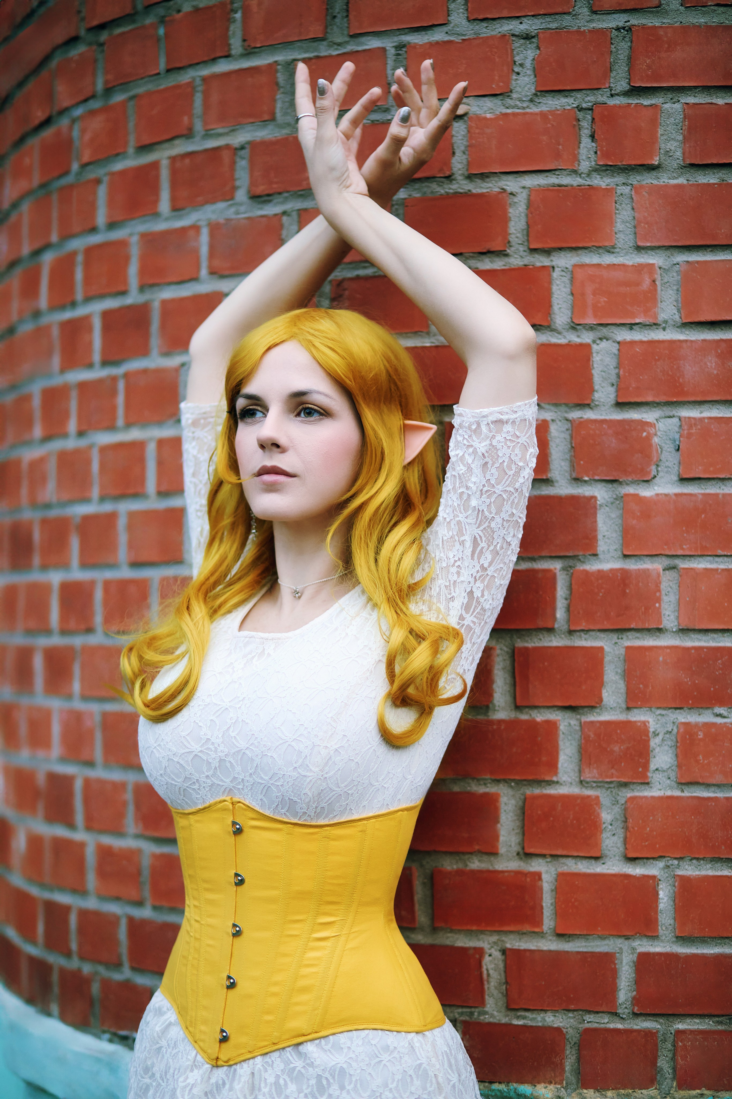 Фэнтези съёмка на фоне кирпичной стены - идея для женского позирования с руками, поднятыми над головой