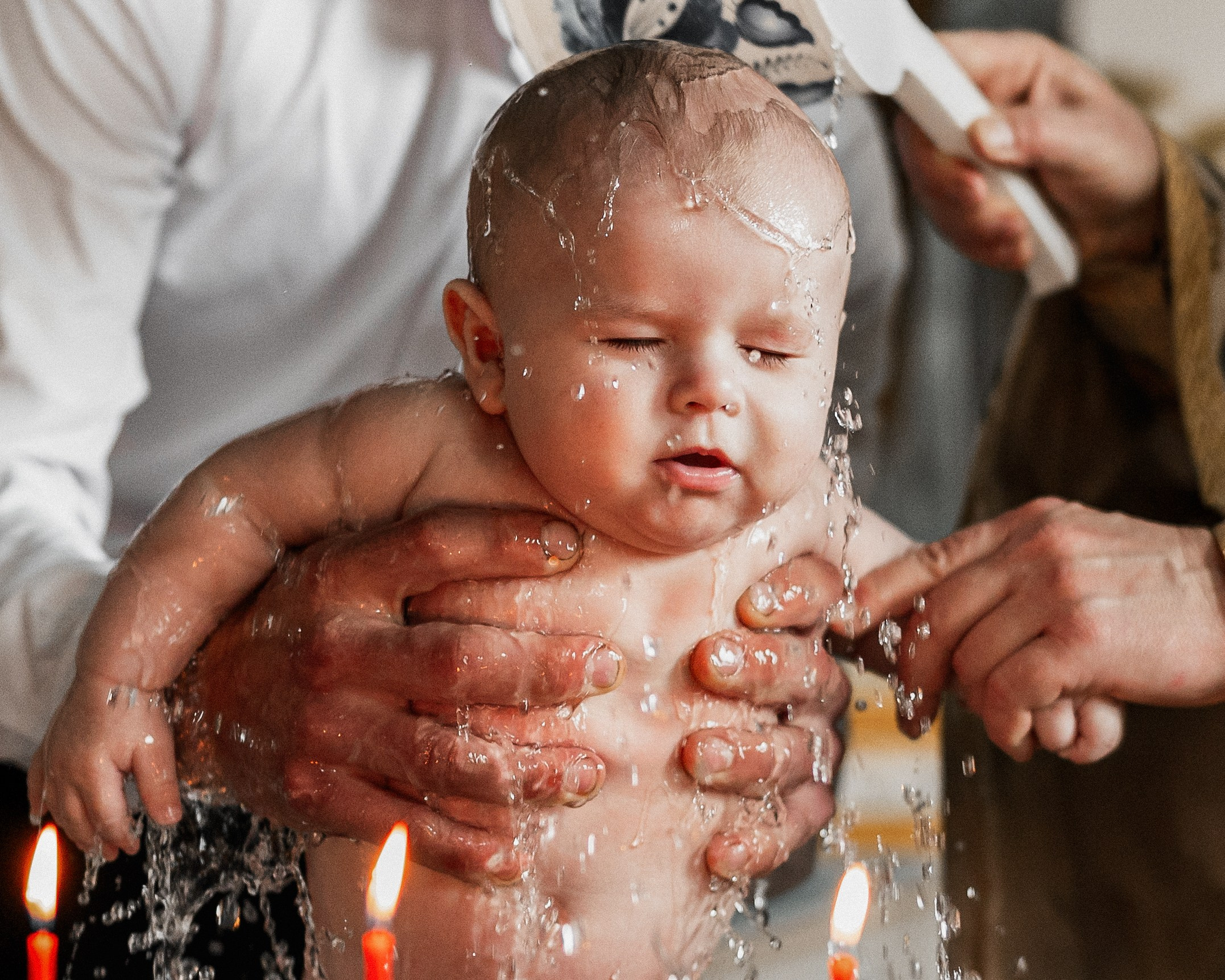 Момент окунания малыша в купель на крещении