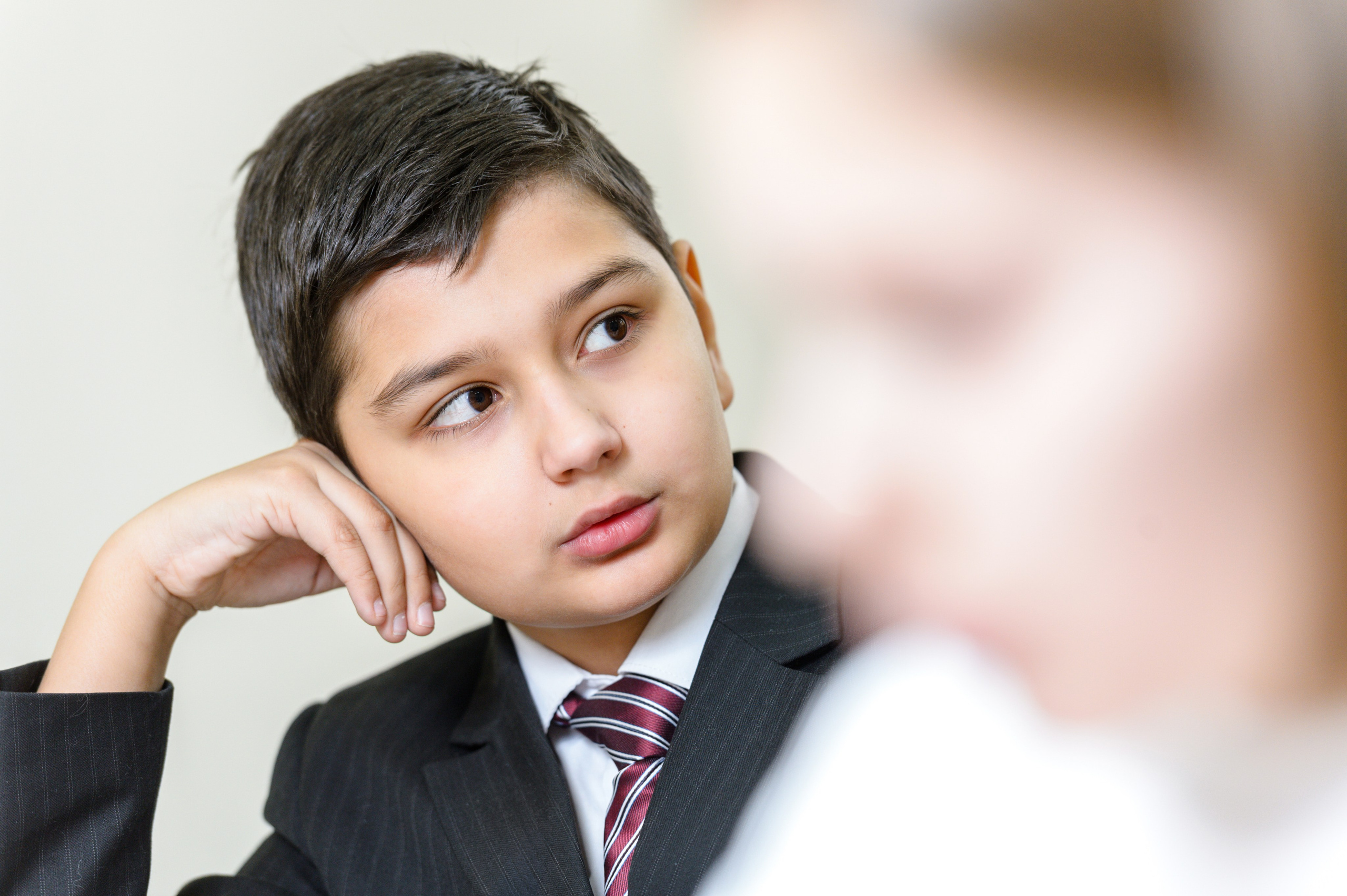 Задумчивый ученик за партой на уроке в классе