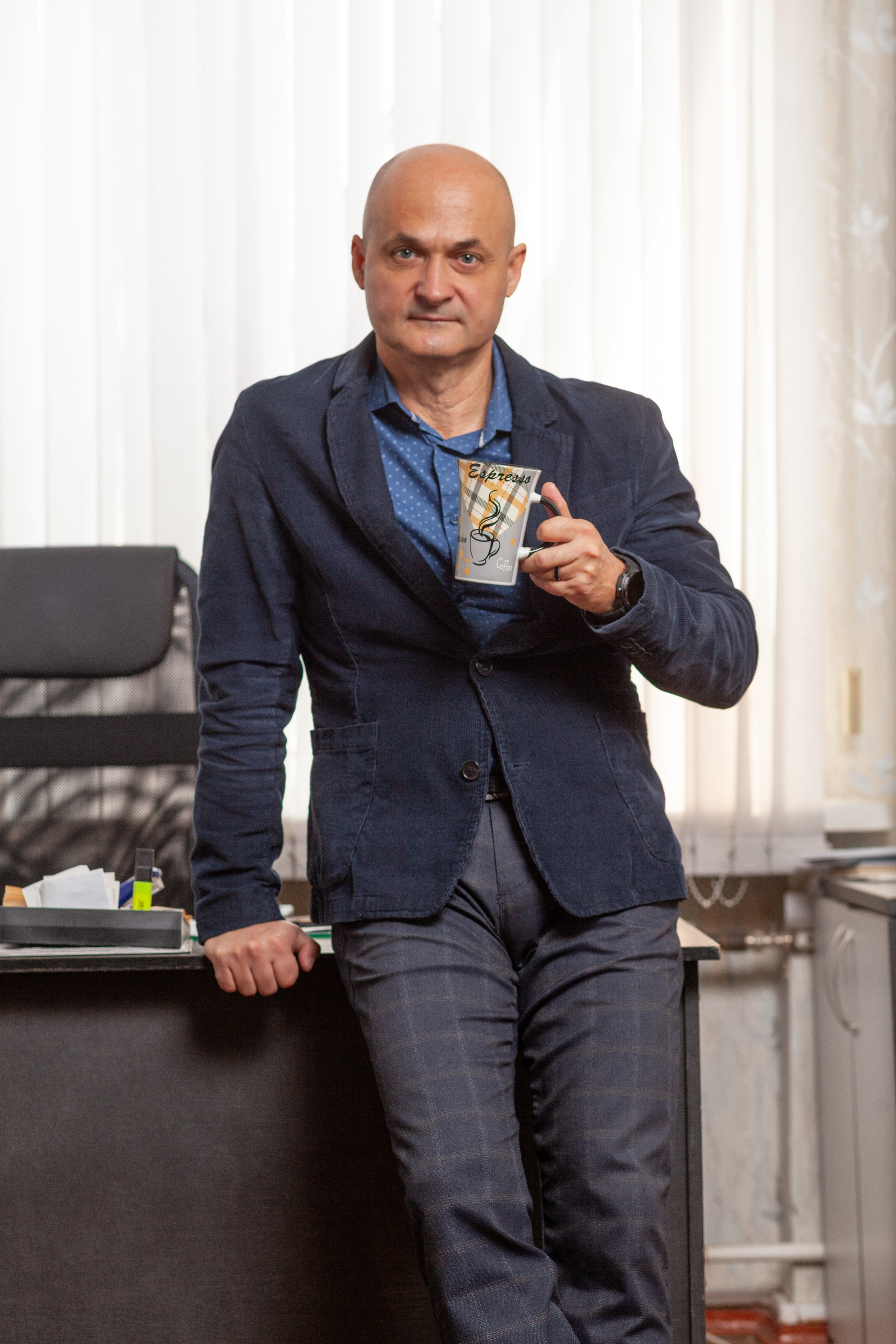 Мужской портрет в офисе с кружкой чая в руке