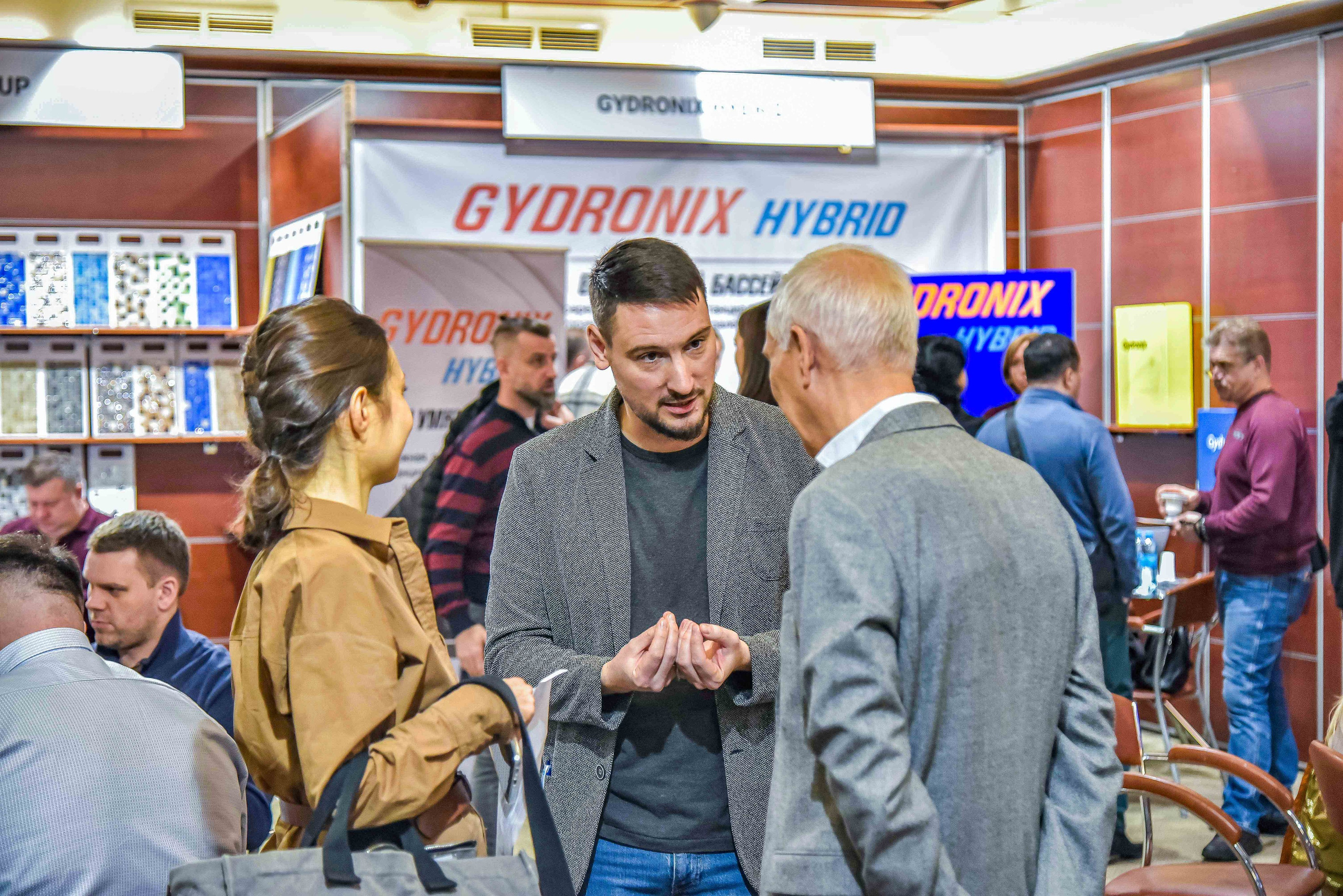 Репортажная съемка с выставки в Москве: снимок передаёт общение между представителем компании и посетителями выставки.