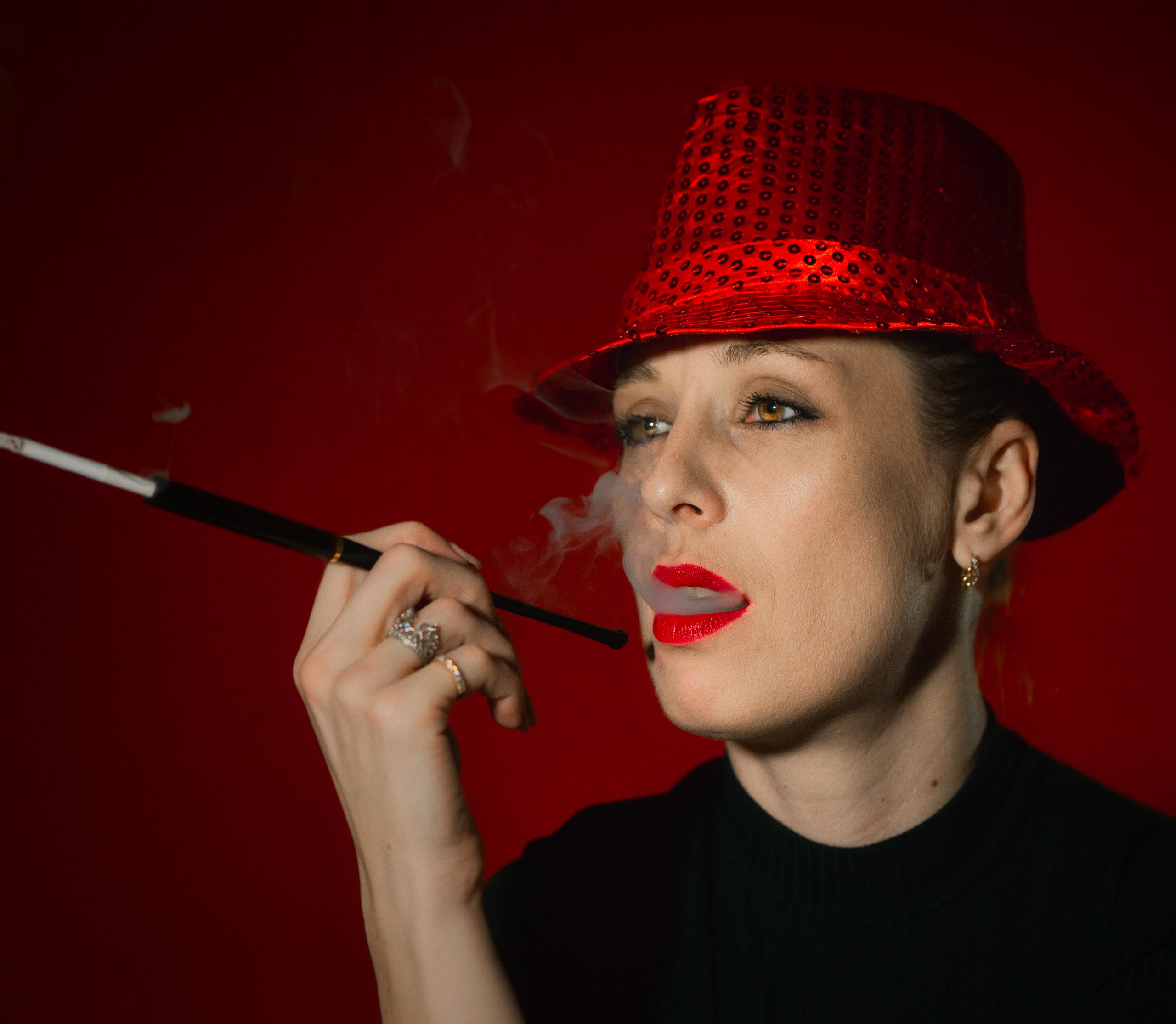 девушка с длинным мундштуком в красной шляпе на красном фоне выпускает дым изо рта портрет
