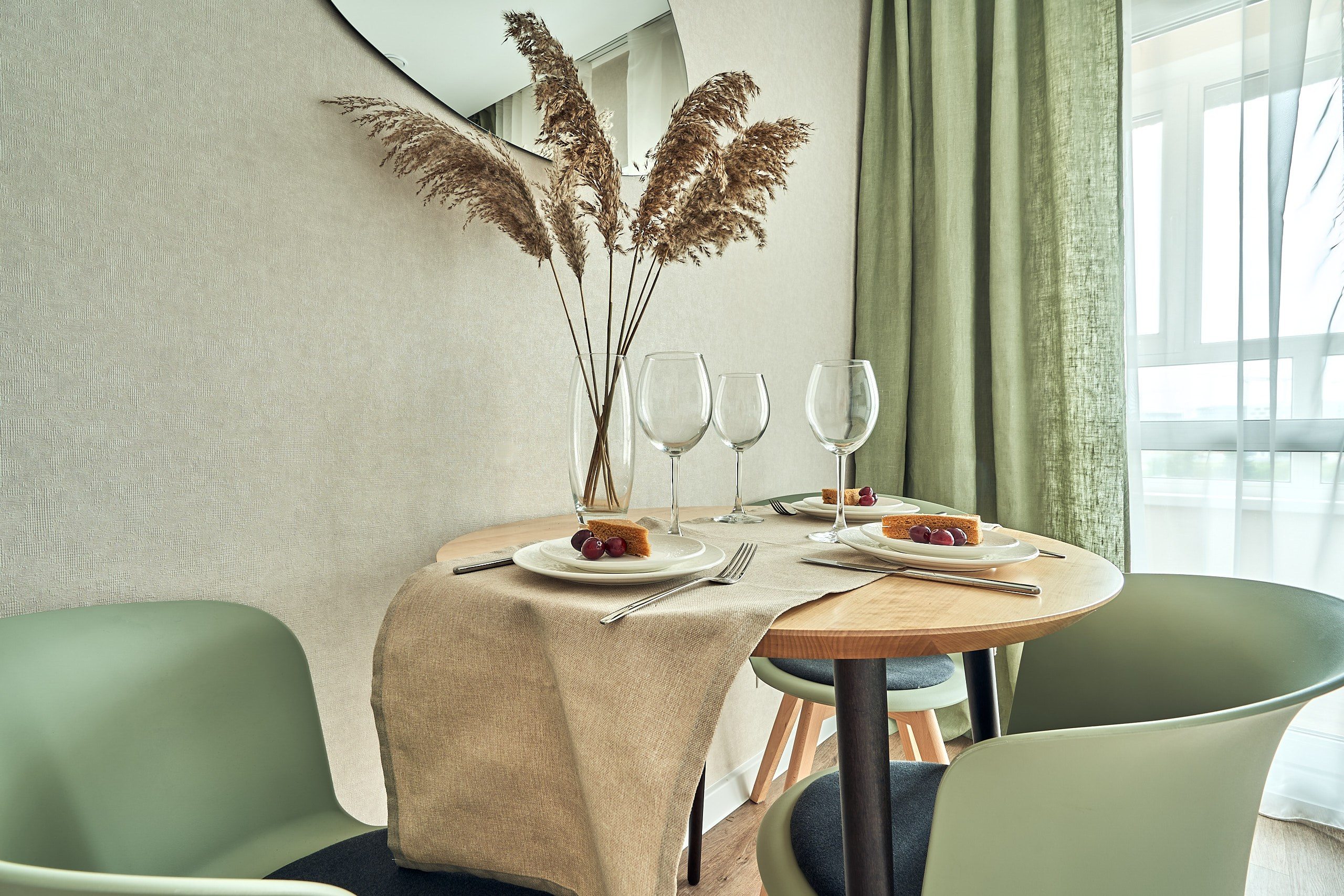 Интерьерная фотография кухни в подмосковных апартаментах, средний план на обеденный стол с посудой и букетом сухих растений