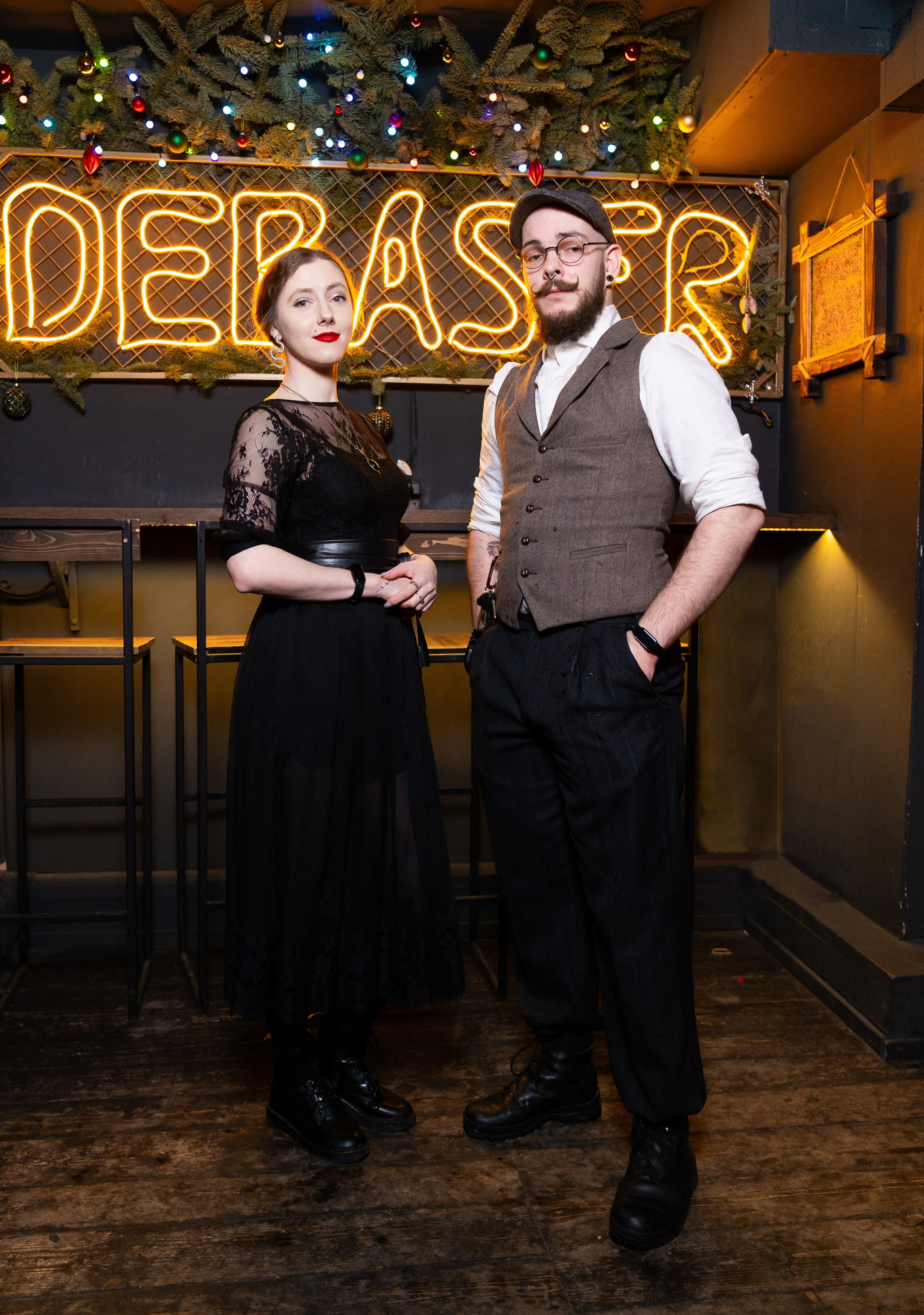 Новогодняя вечеринка 2026 в баре Debaser (Санкт-Петербург). Пара позирует на фоне неоновой вывески DEBASER. Фото Евгения Мальцева.