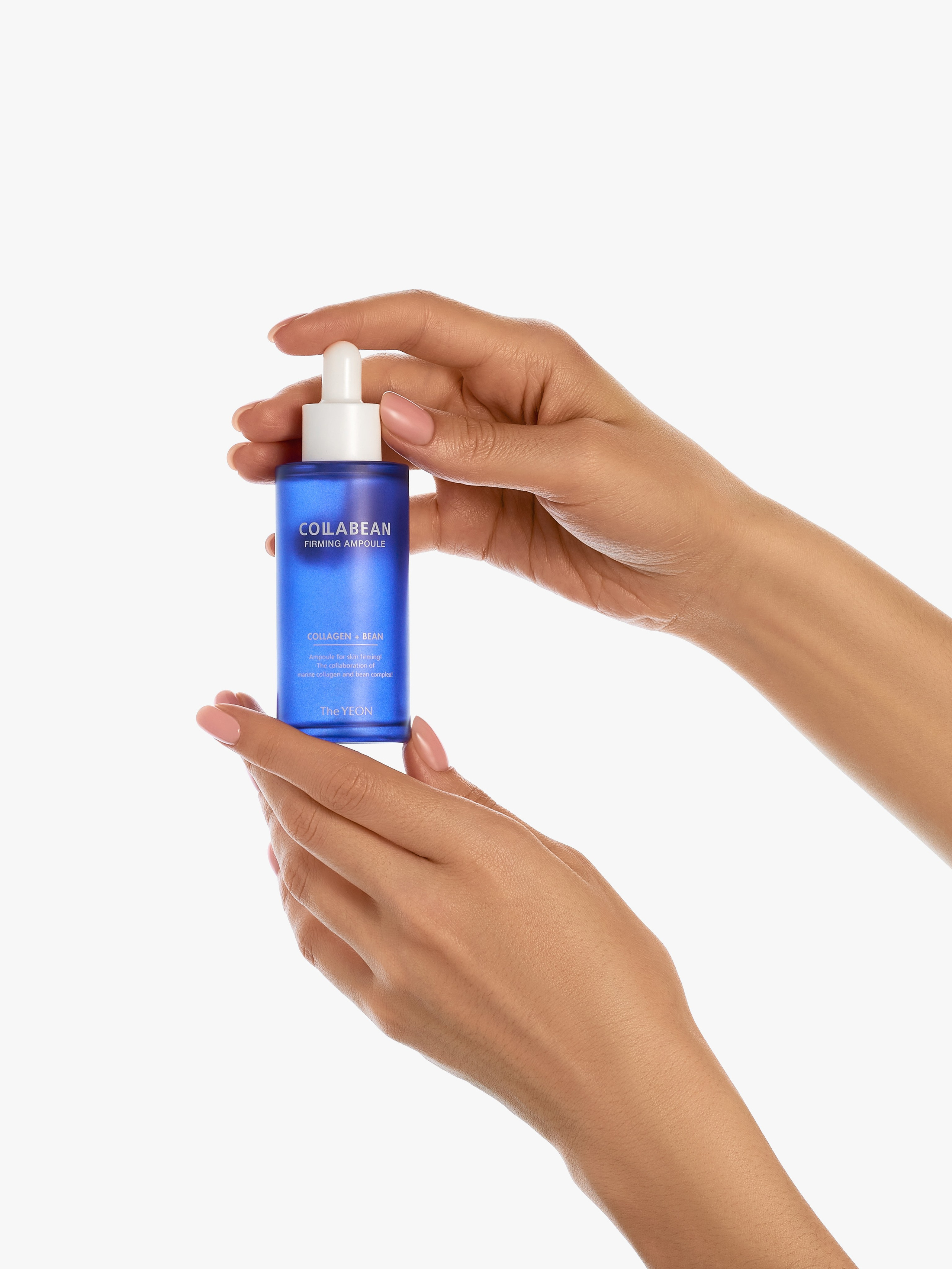 Синяя бутылочка с белой пипеткой в руках девушки на белом фоне