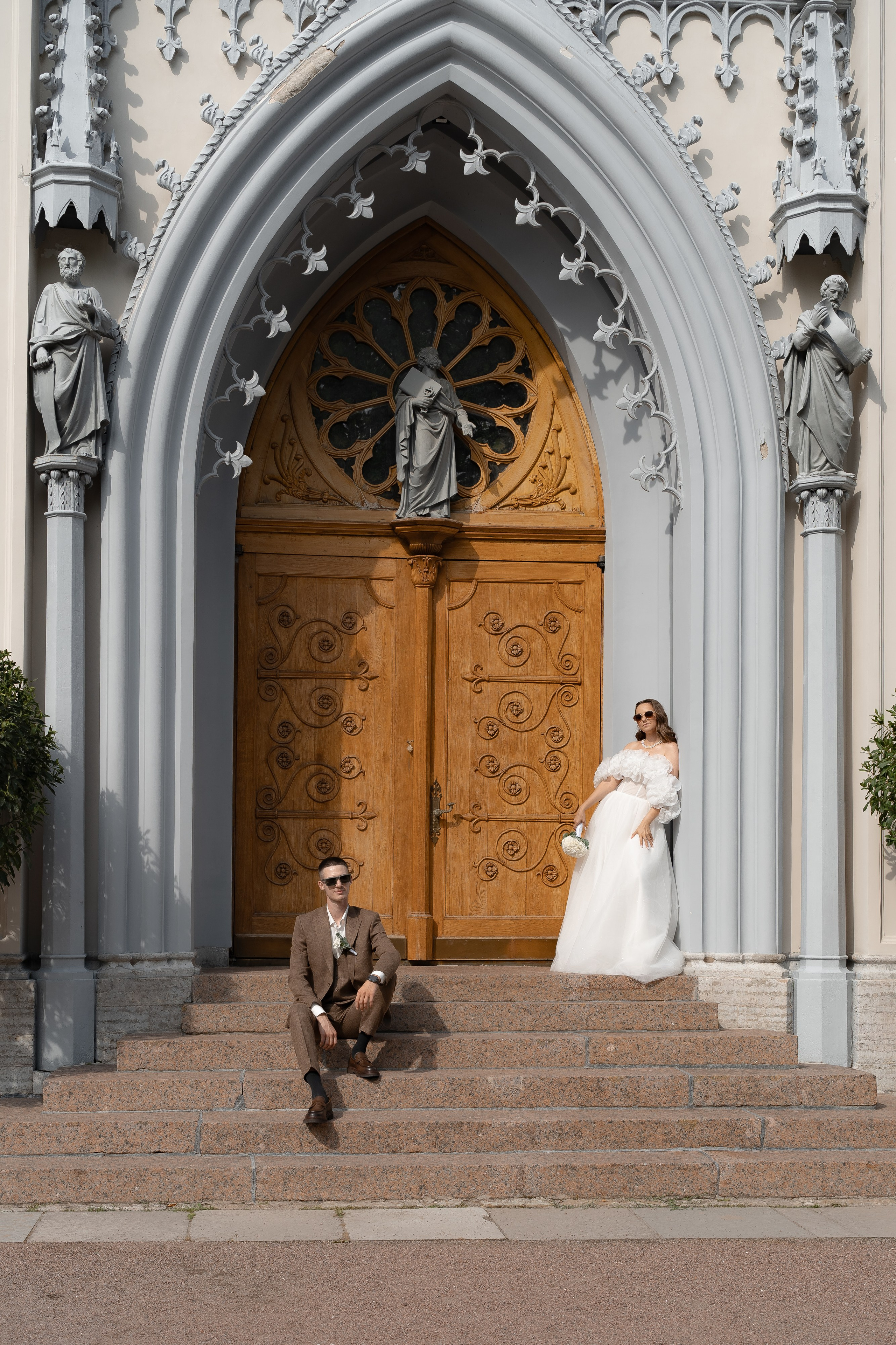 Свадебный кадр у готической капеллы в Петергофе — жених и невеста на фоне арки и деревянных дверей