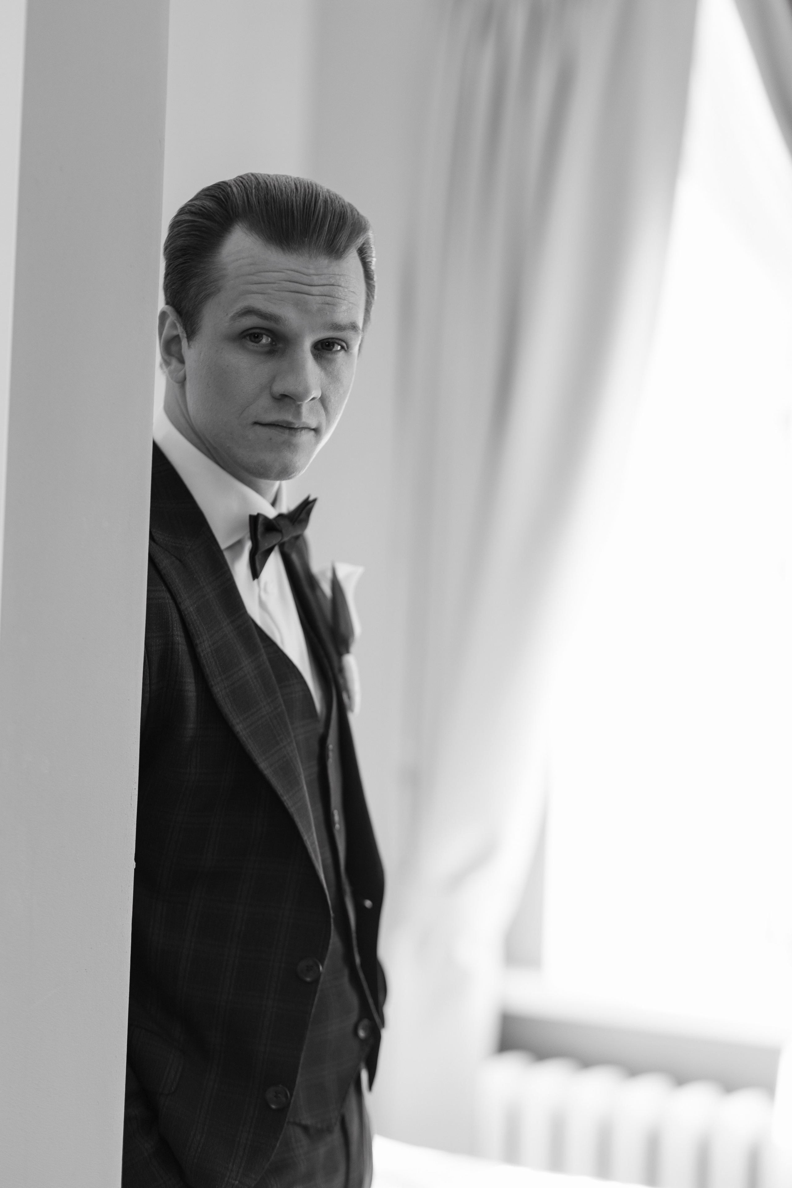 Жених стоит у окна фото в черно белом цвете.