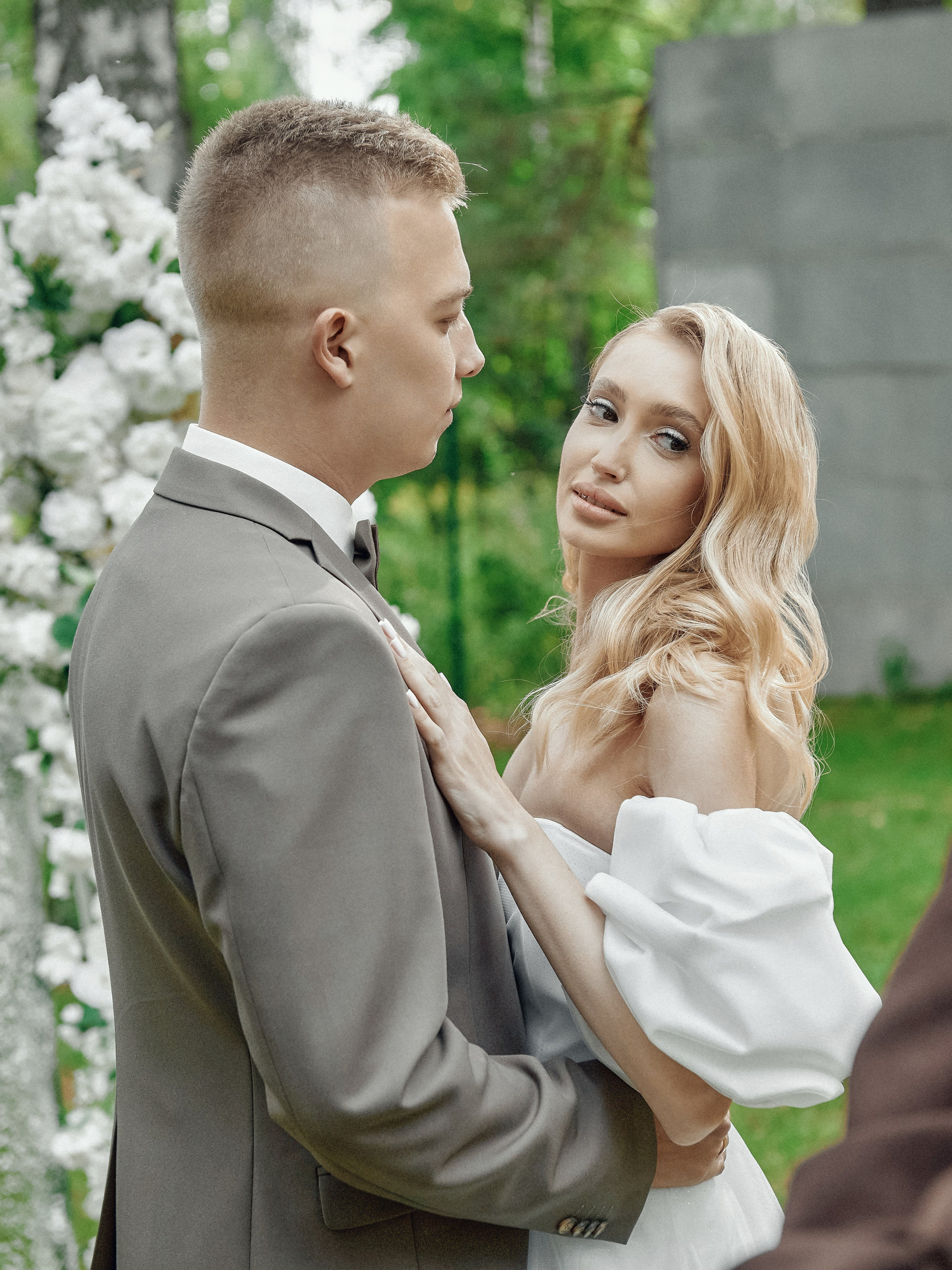Жених и невеста обнимаются у арки на свадьбе в лесу, романтическая фотосессия»