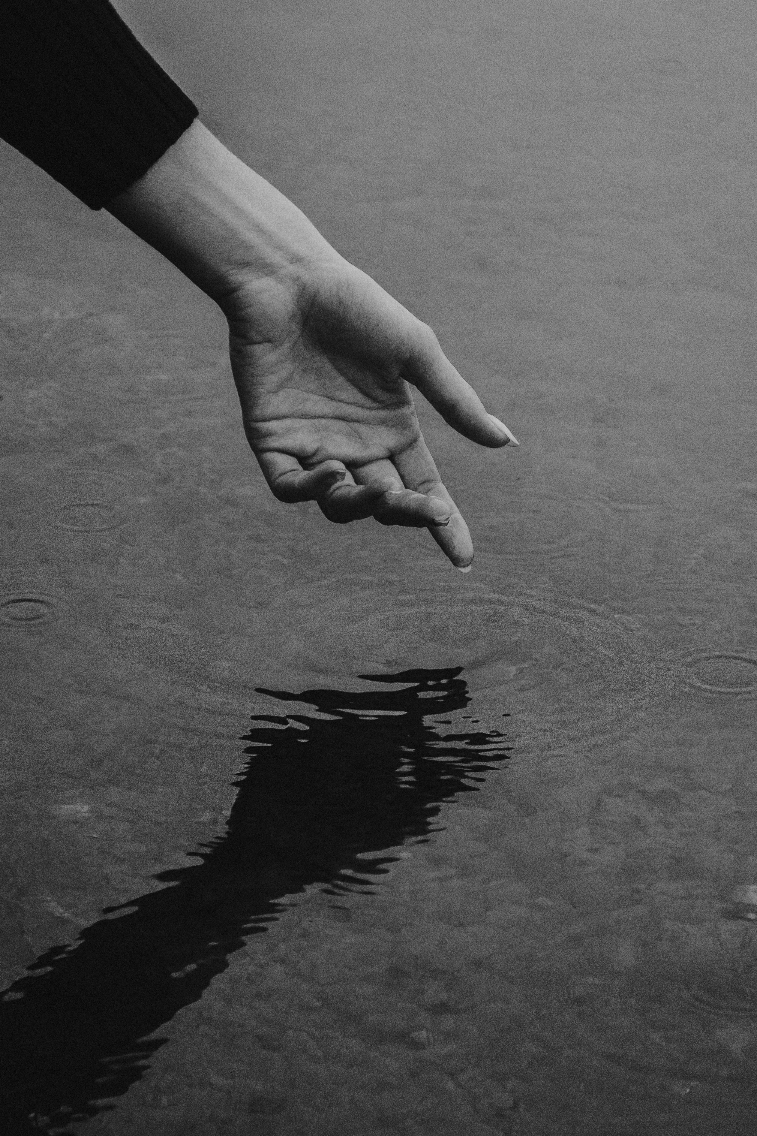 Рука, тянущаяся к воде и оставляющая круги на ней