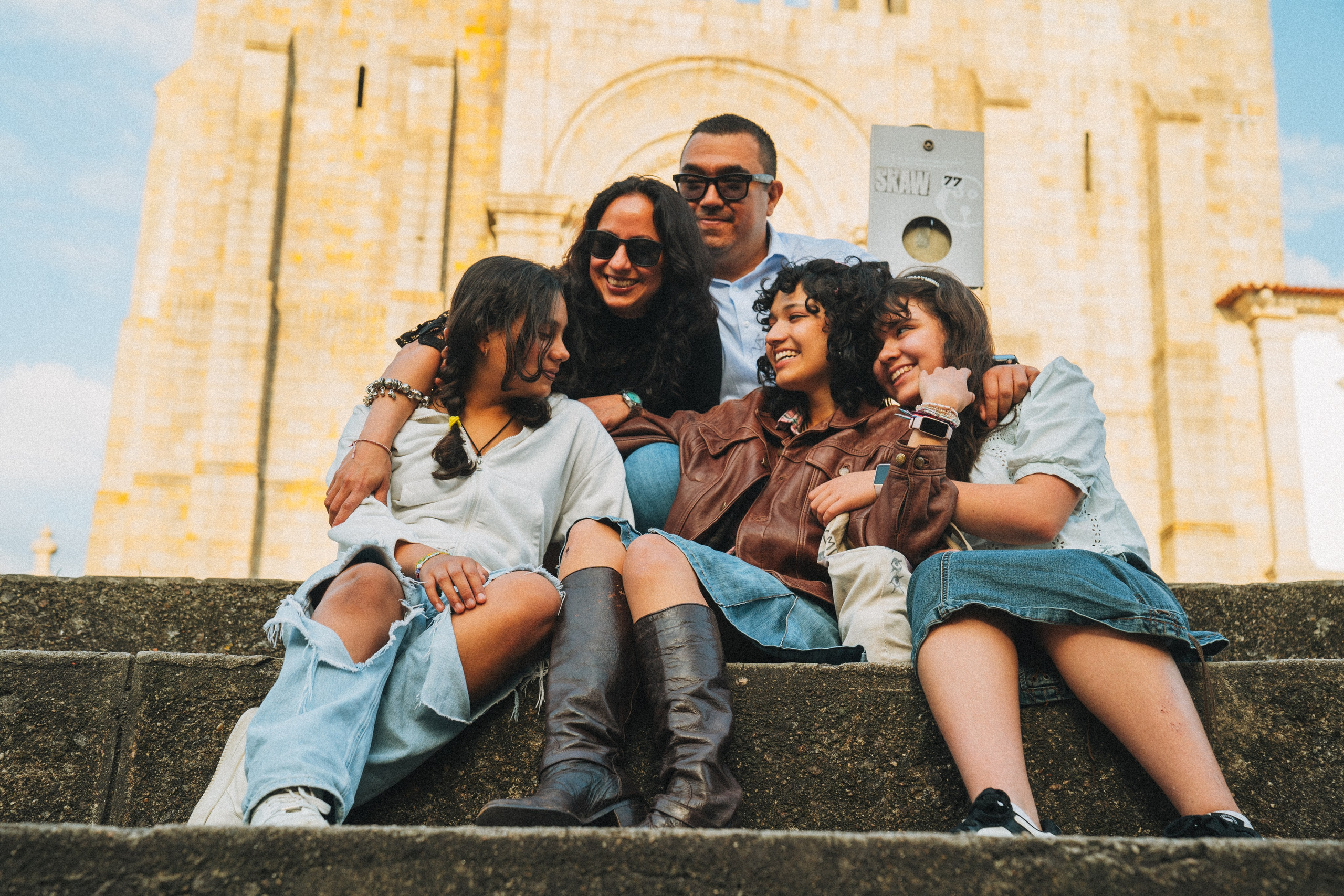 Группа людей гуляет по живописной узкой улочке в Португалии, окружённой старыми домами и зеленью.