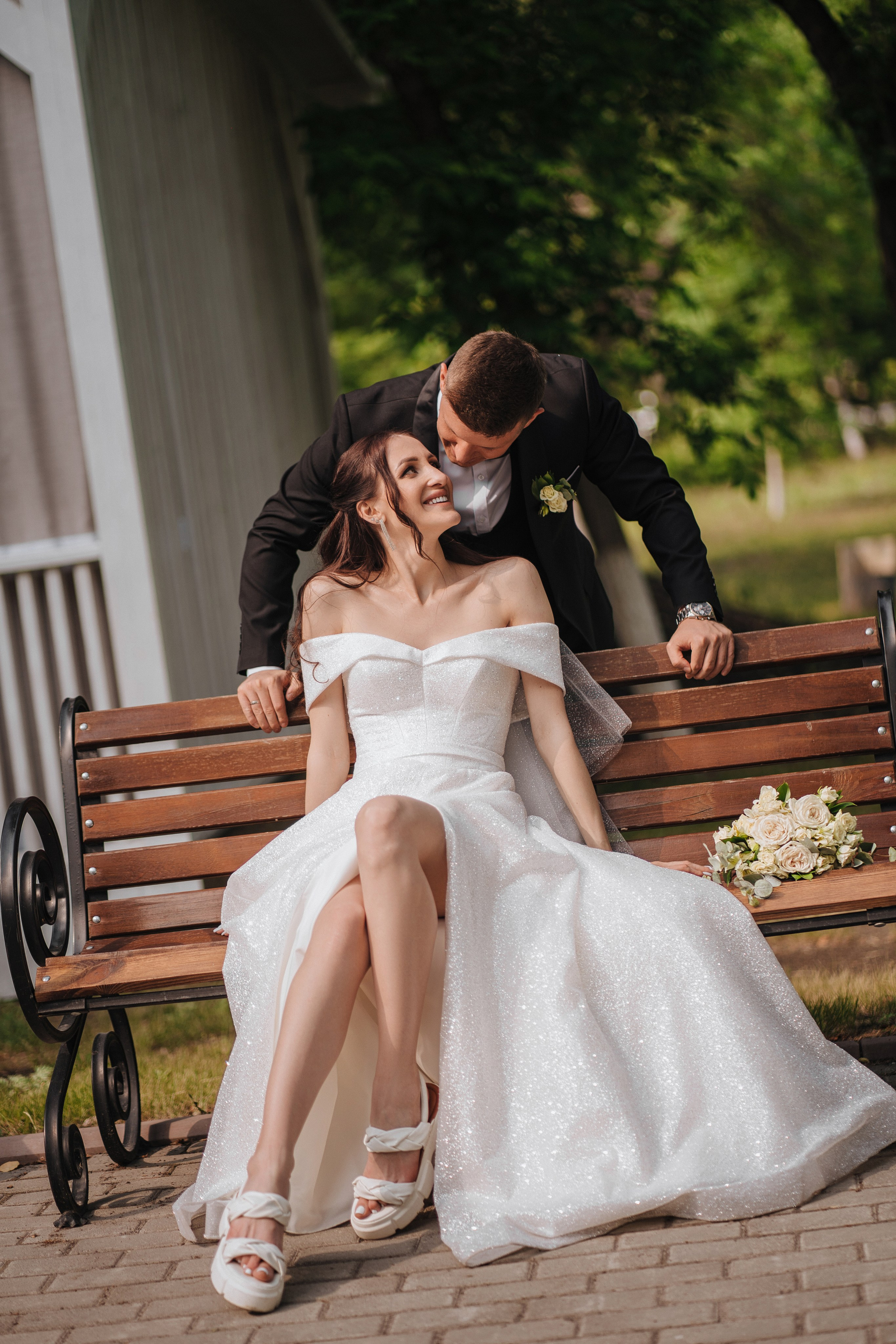 Невеста на лавочке, жених наклоняется к ней