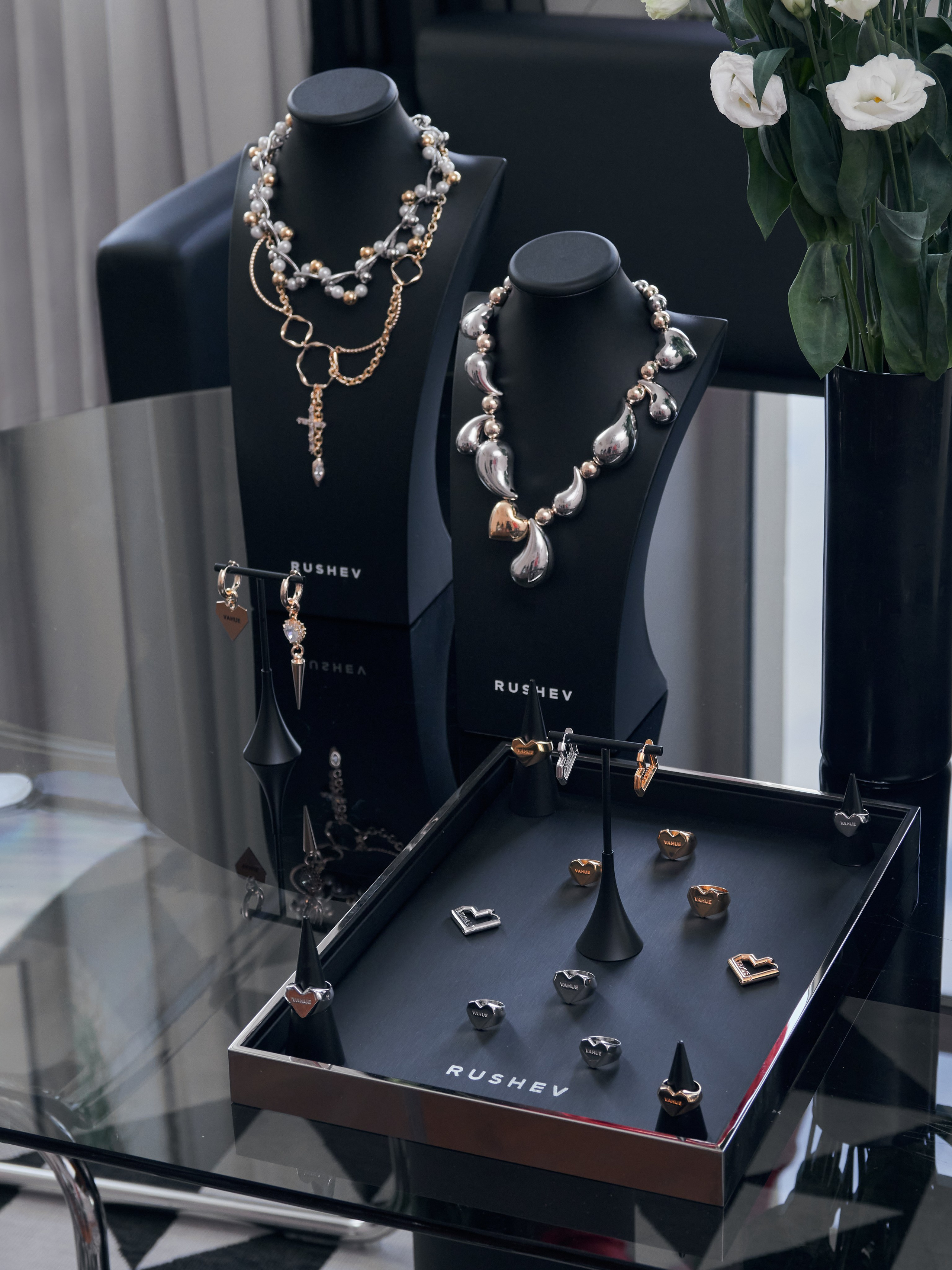 Элегантная ювелирная витрина с ожерельями, серьгами и кольцами на черных подставках с логотипом бренда  "РУШЕВ" RUSHEV