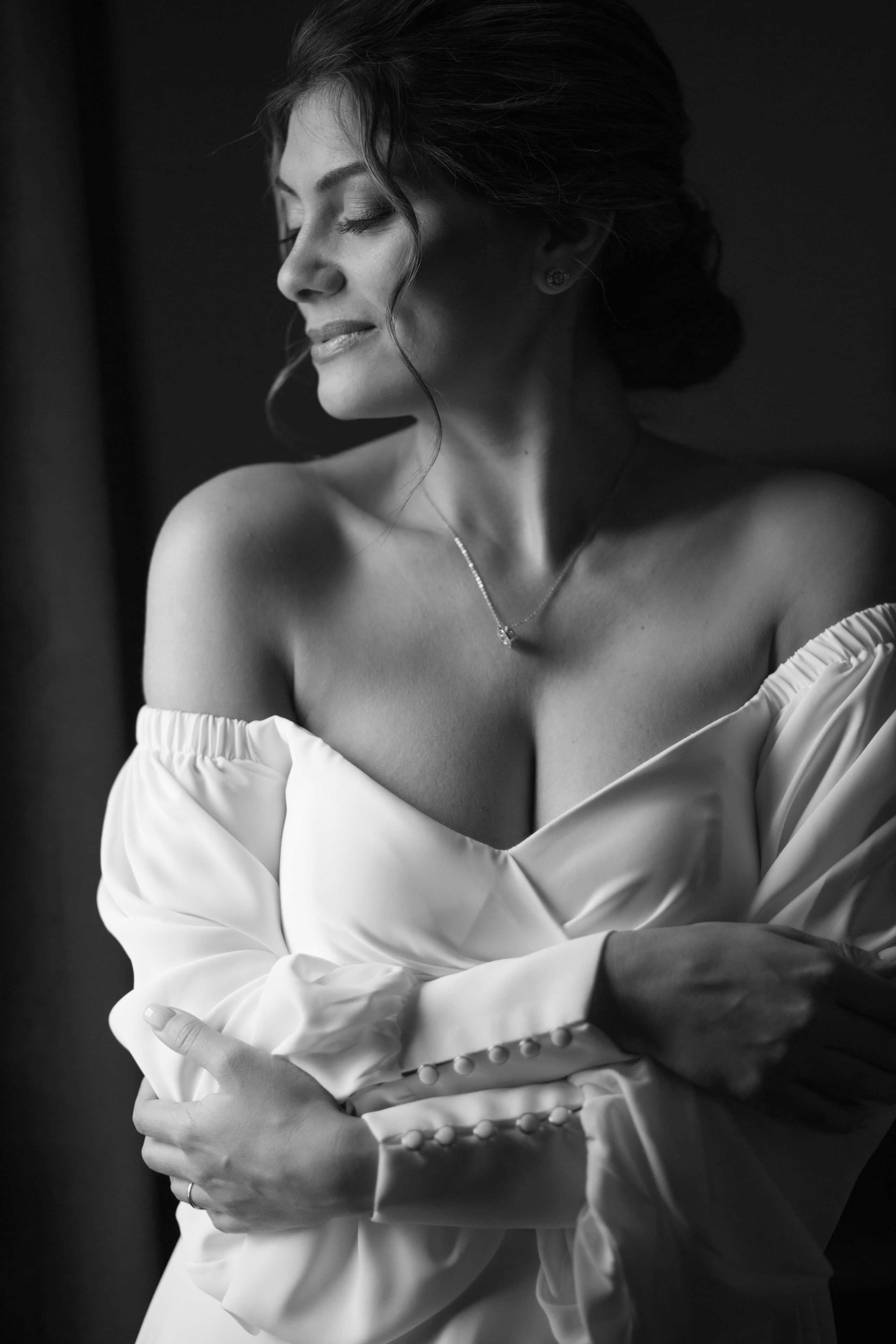 красивая невеста смотрит в окно перед выходом к жениху, фотография черно-белая