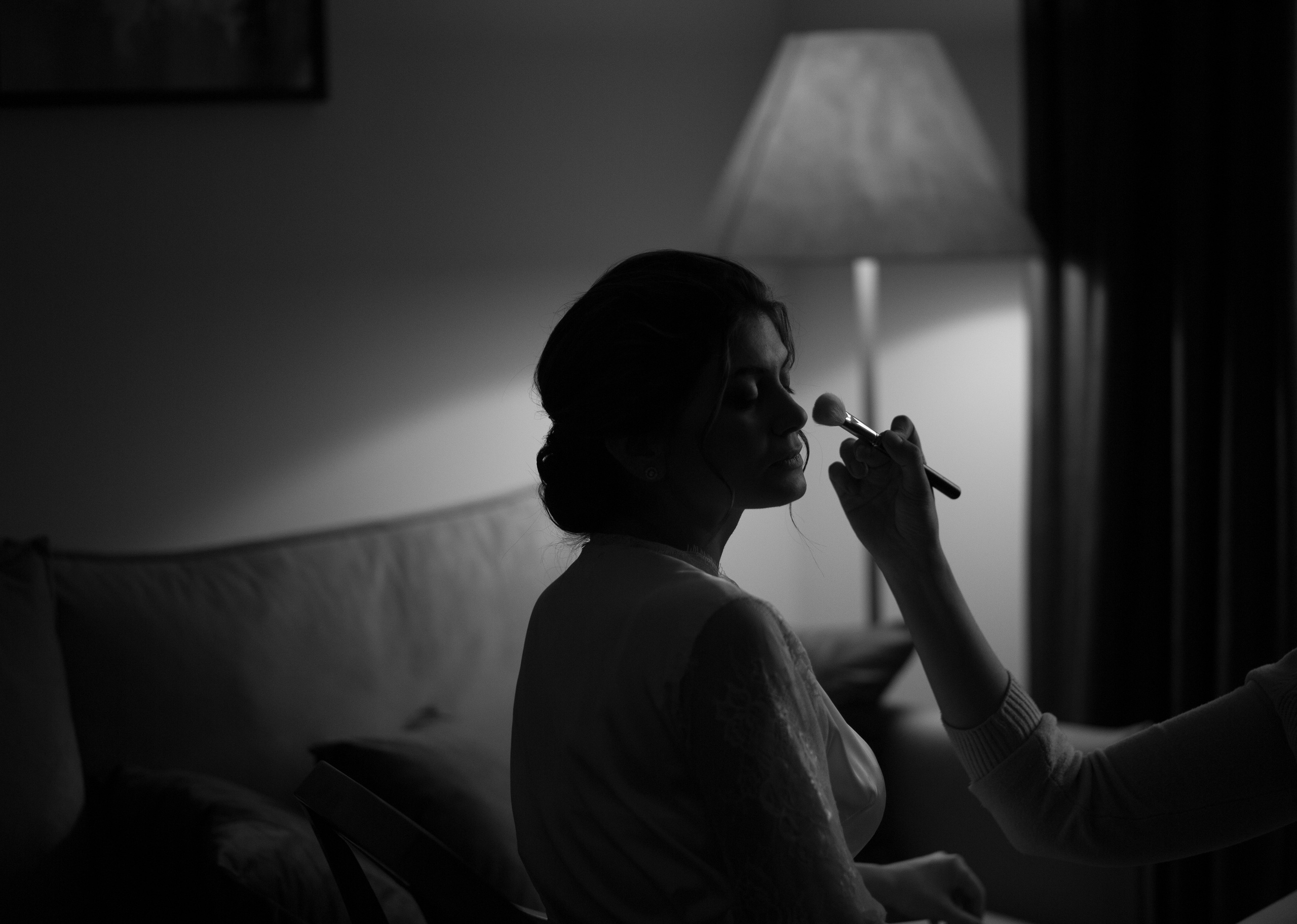 в номере отеля несту красит визажист, на заднем плане торшер заполняет своим светом комнату