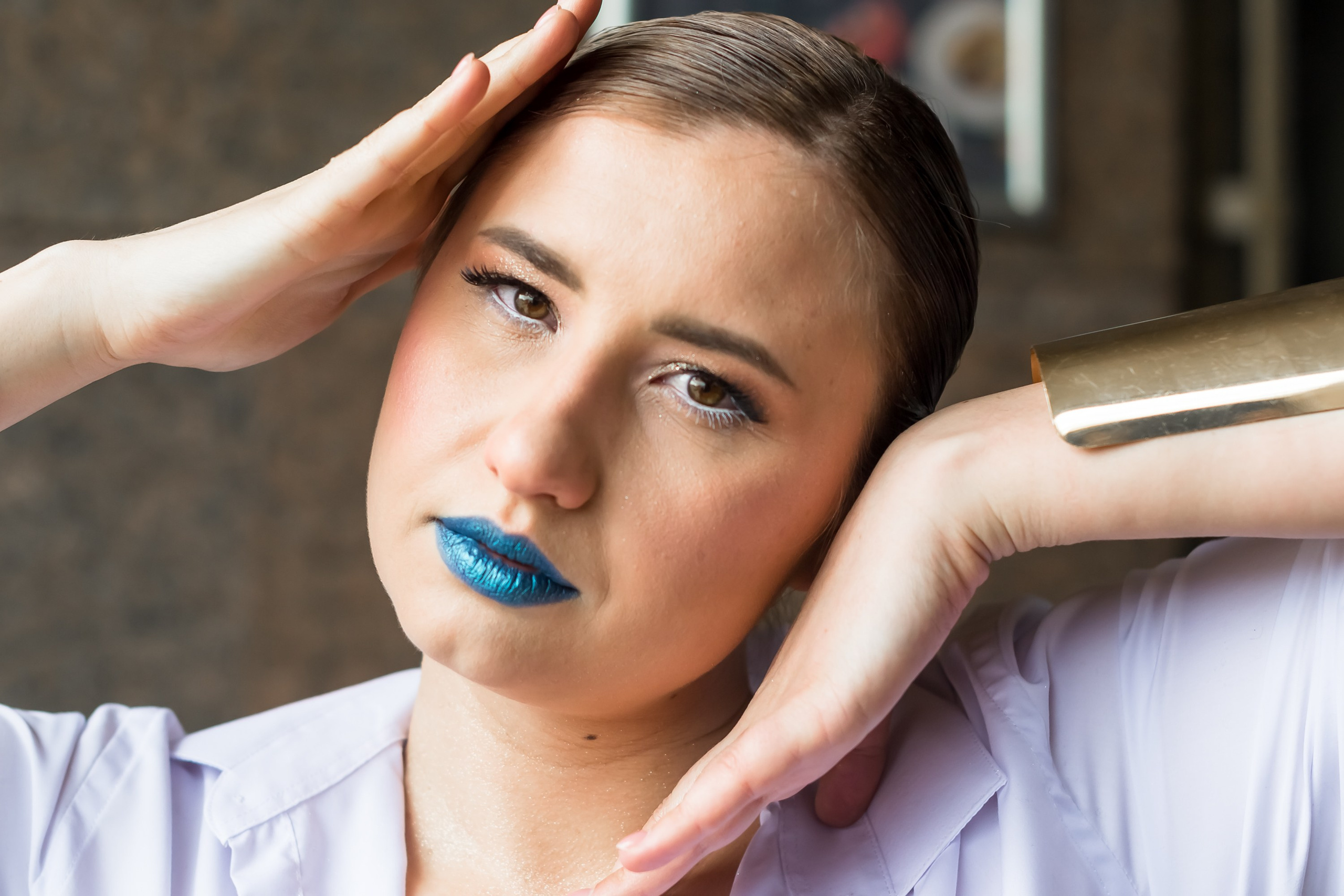 На фото девушка в белой рубашке держит руками голову.