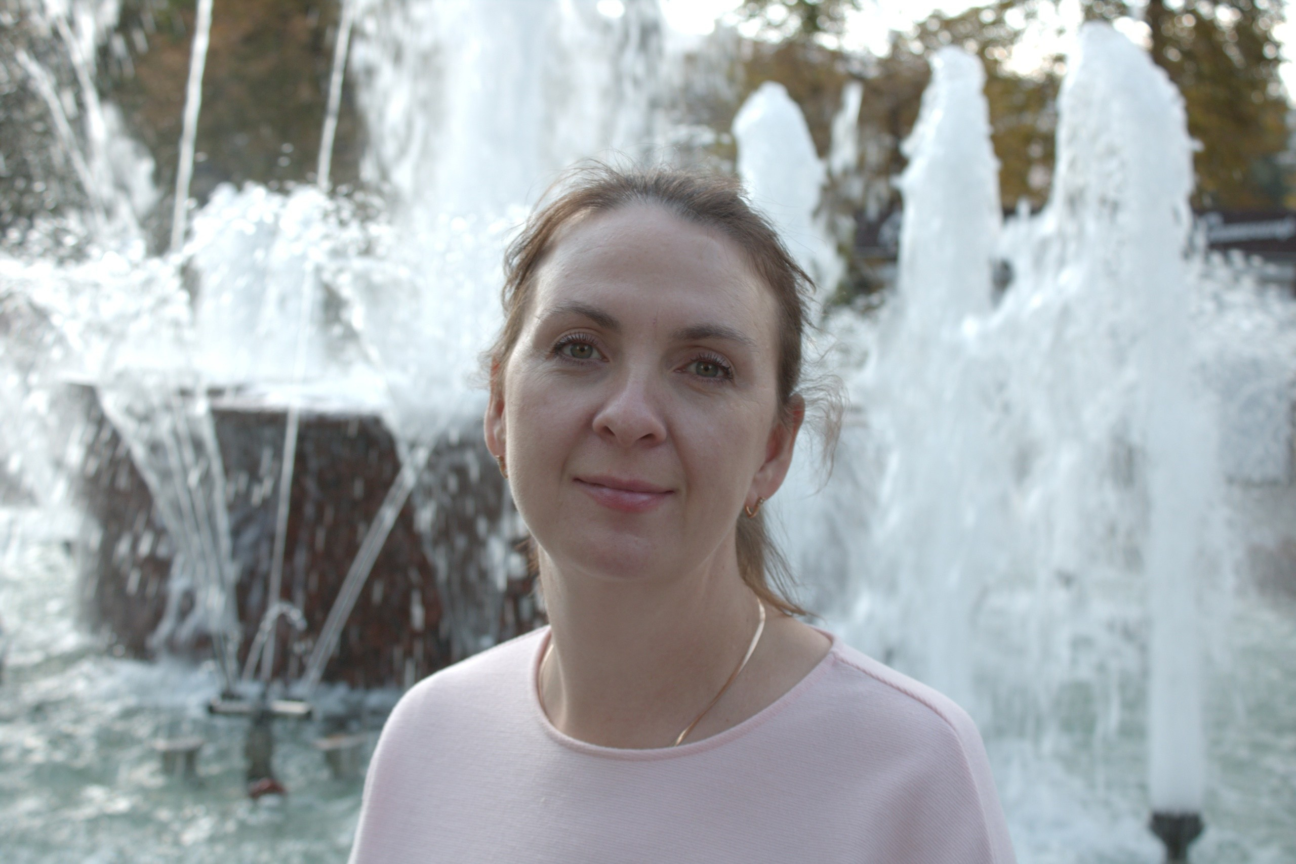 красивая девушка стоит у фонтана