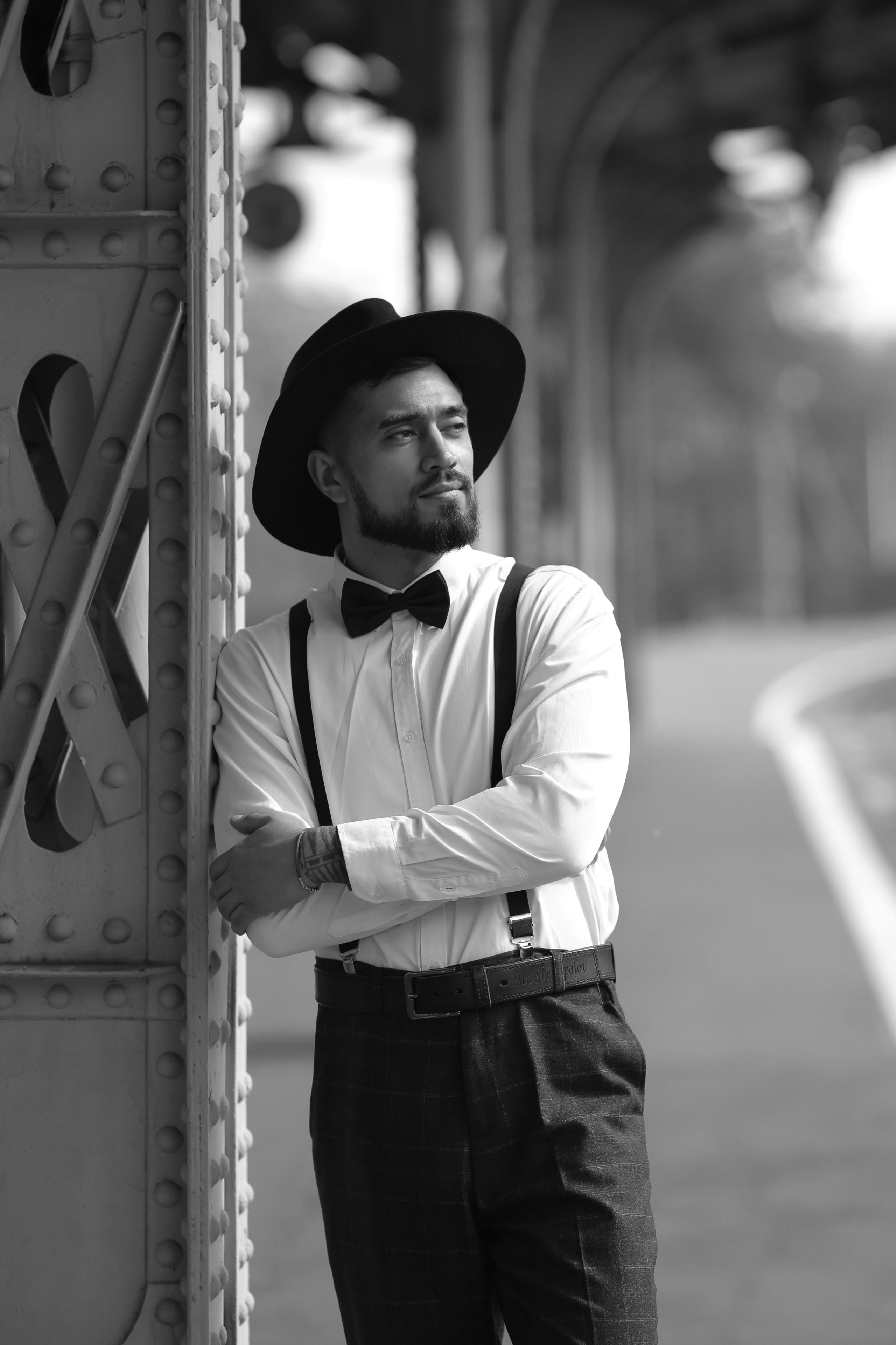 Мужчина с бородой в брюках с подтяжками, белой рубашке с бабочкой и в шляпе