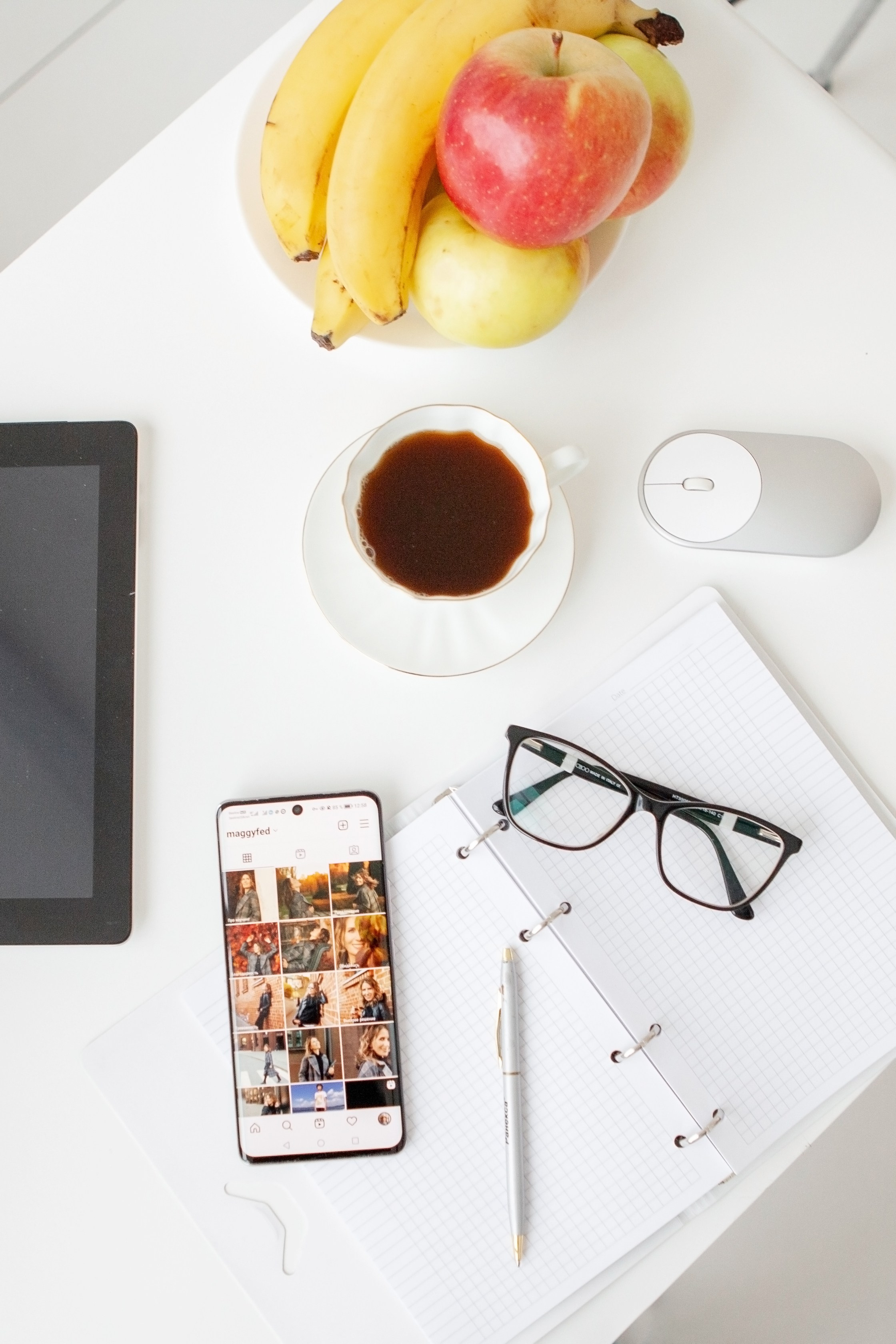 рабочий стол офисного сотрудника: компьютер, смартфон, кофе, очки, фрукты, наушники и хорошее настроение.