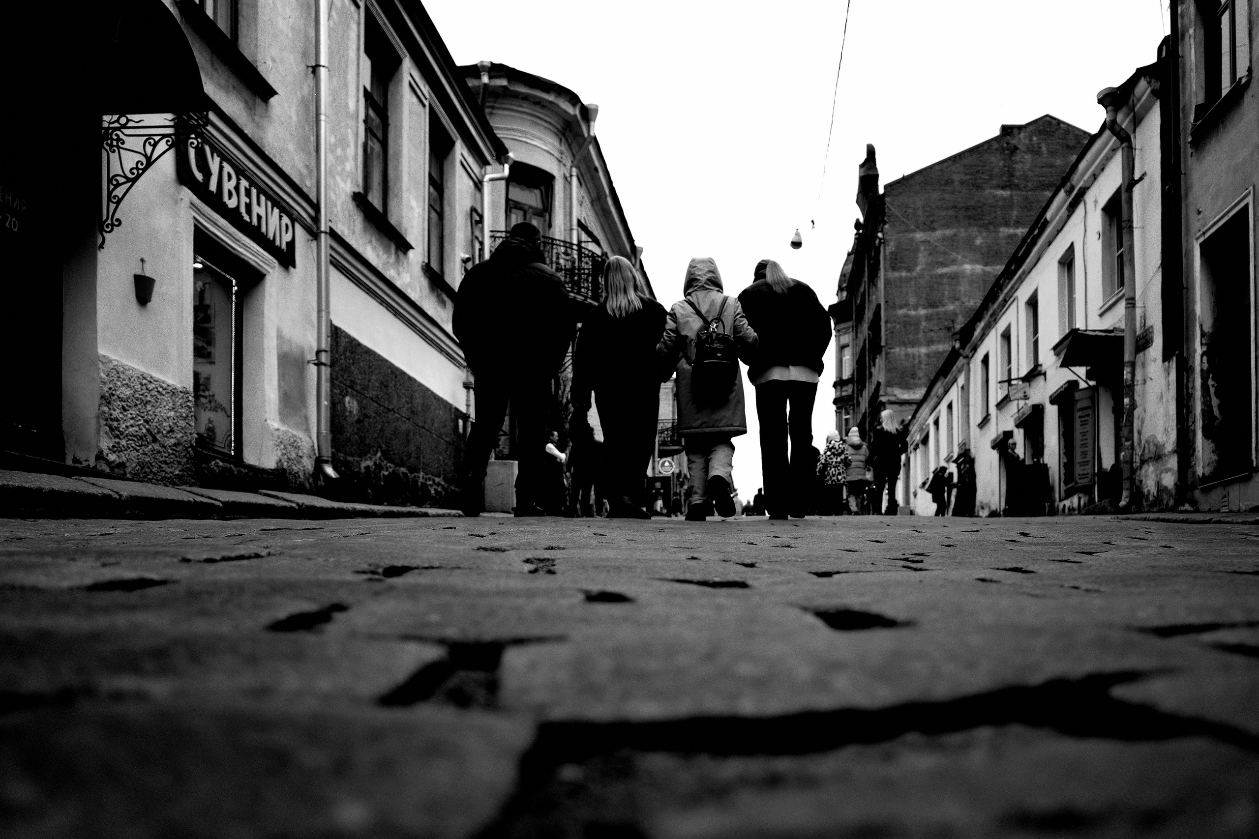 Четверо идут вверх по улице по брусчатке в Выборге