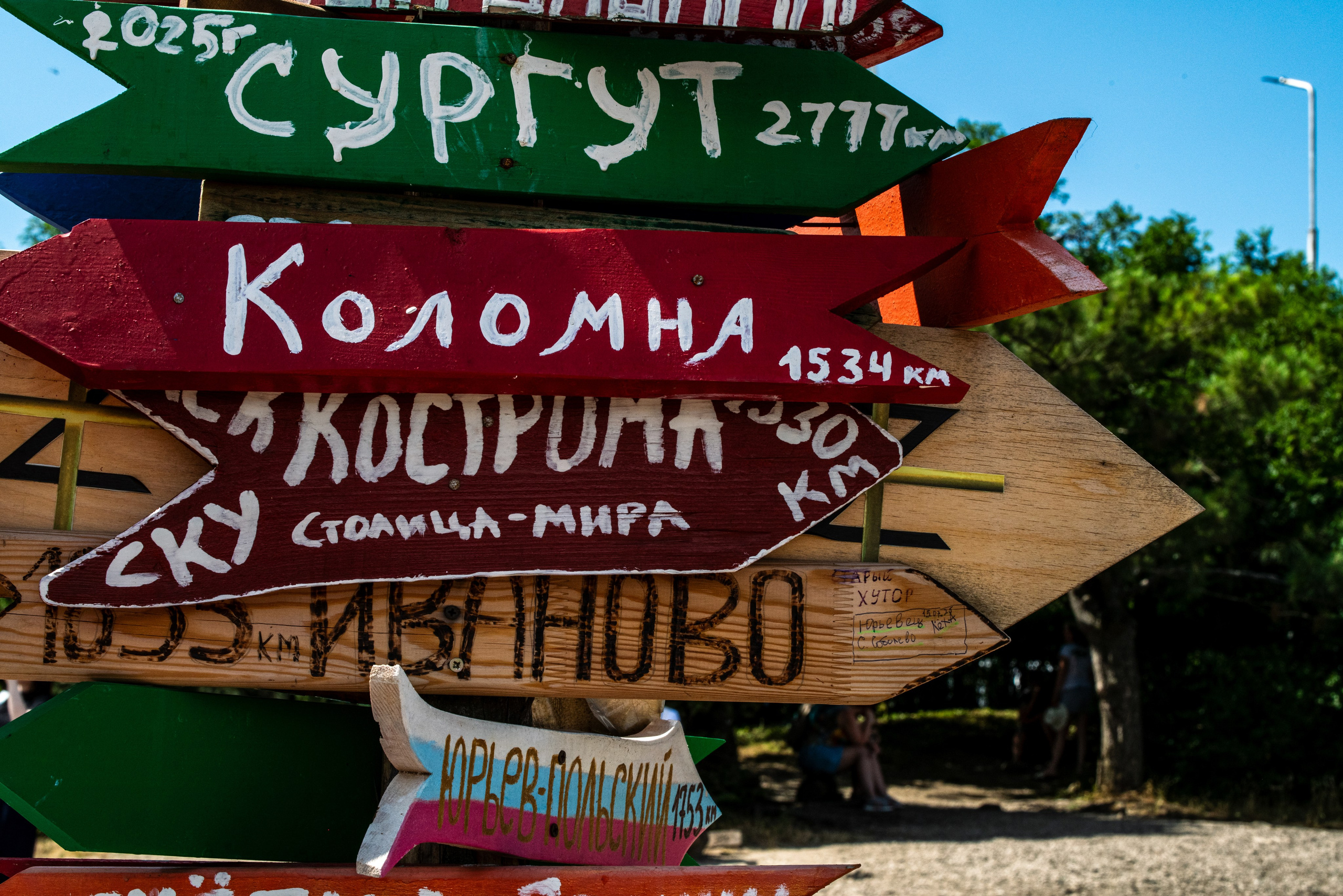 На изображении несколько указателей с названиями городов и расстояниями до них, установленными на горе Машук