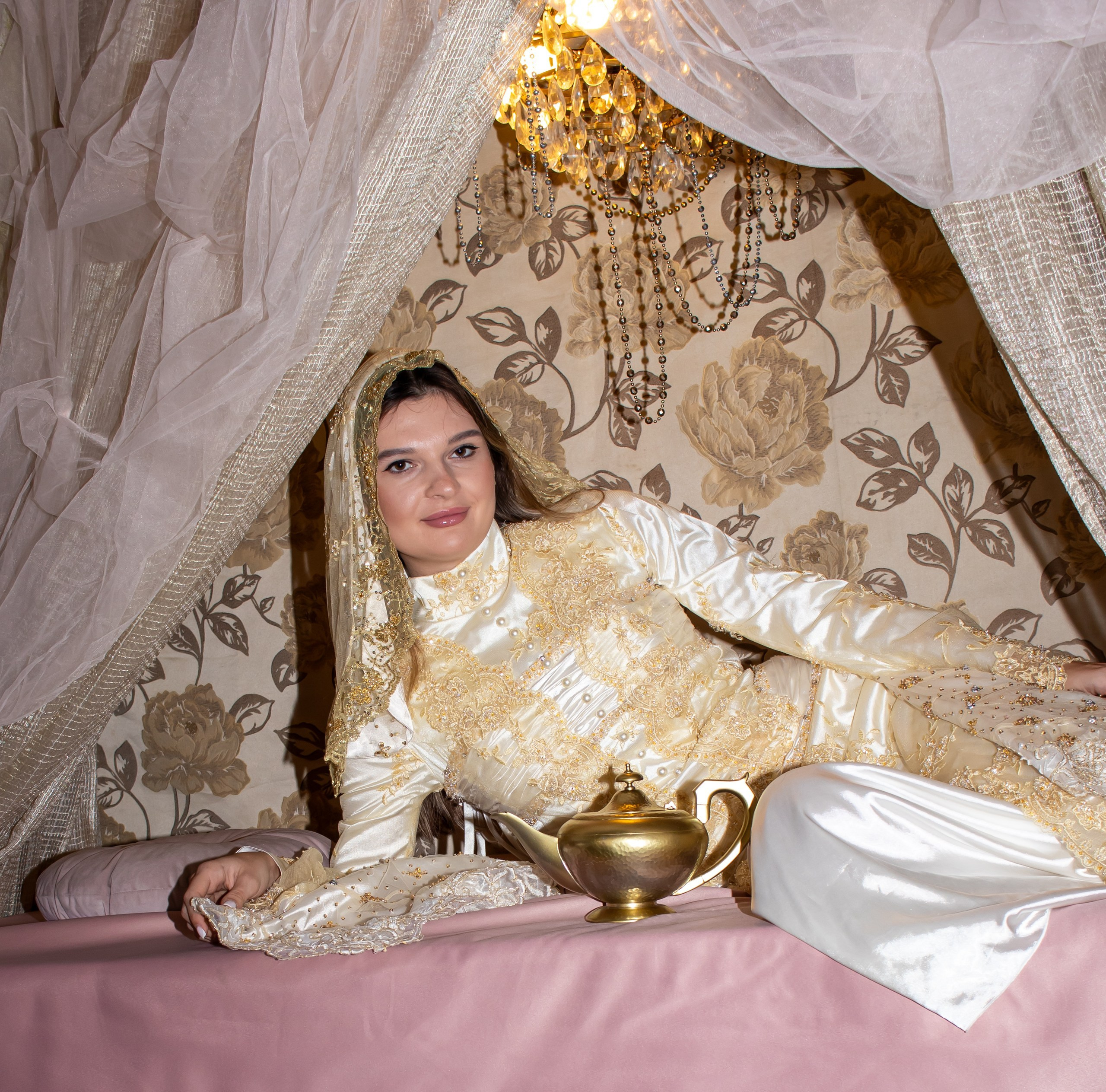 Девушка в золотом наряде лежит на подушках в восточной фотозоне — фотограф Карасёва Елена