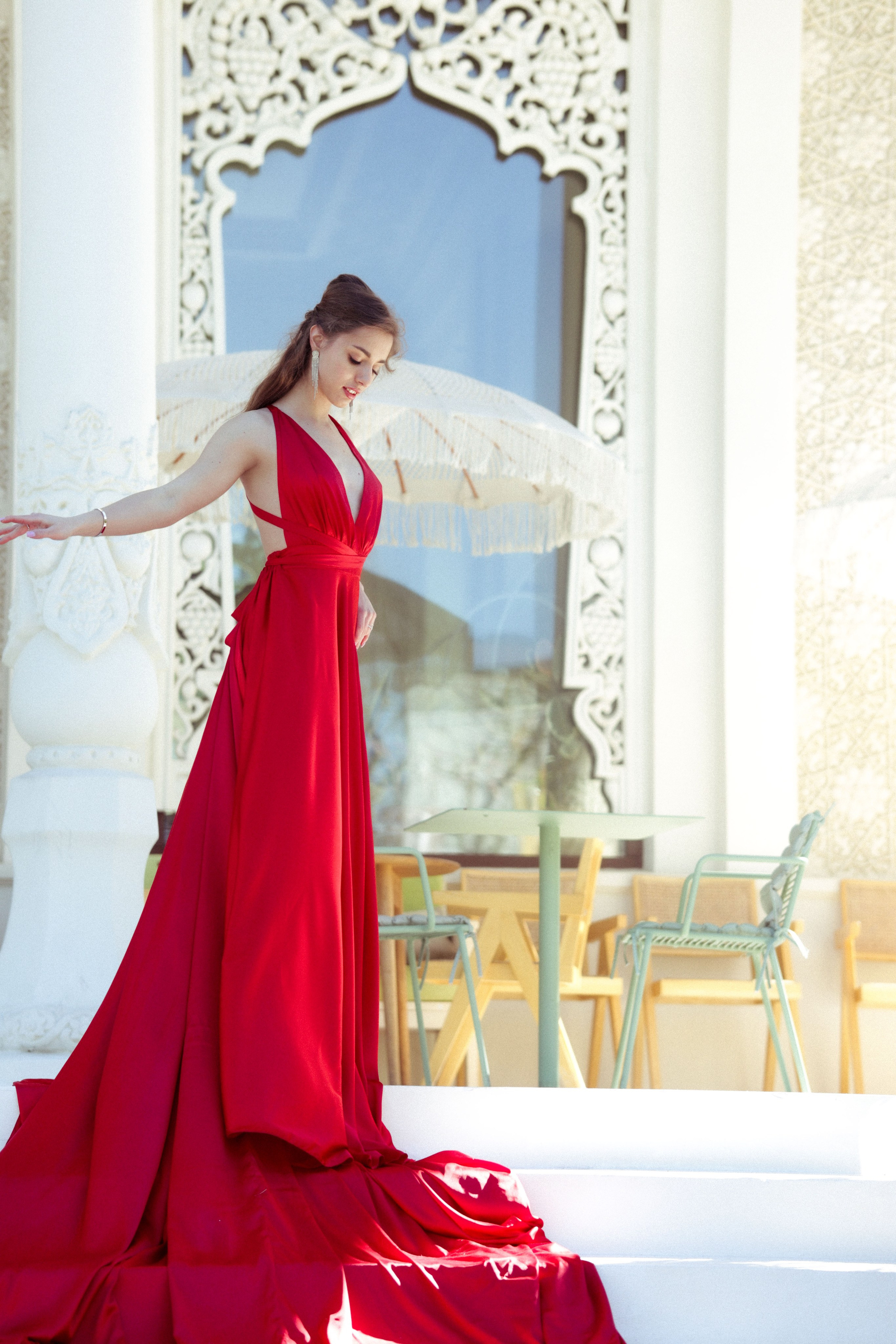 женщина в алом платье на фоне белых колонн