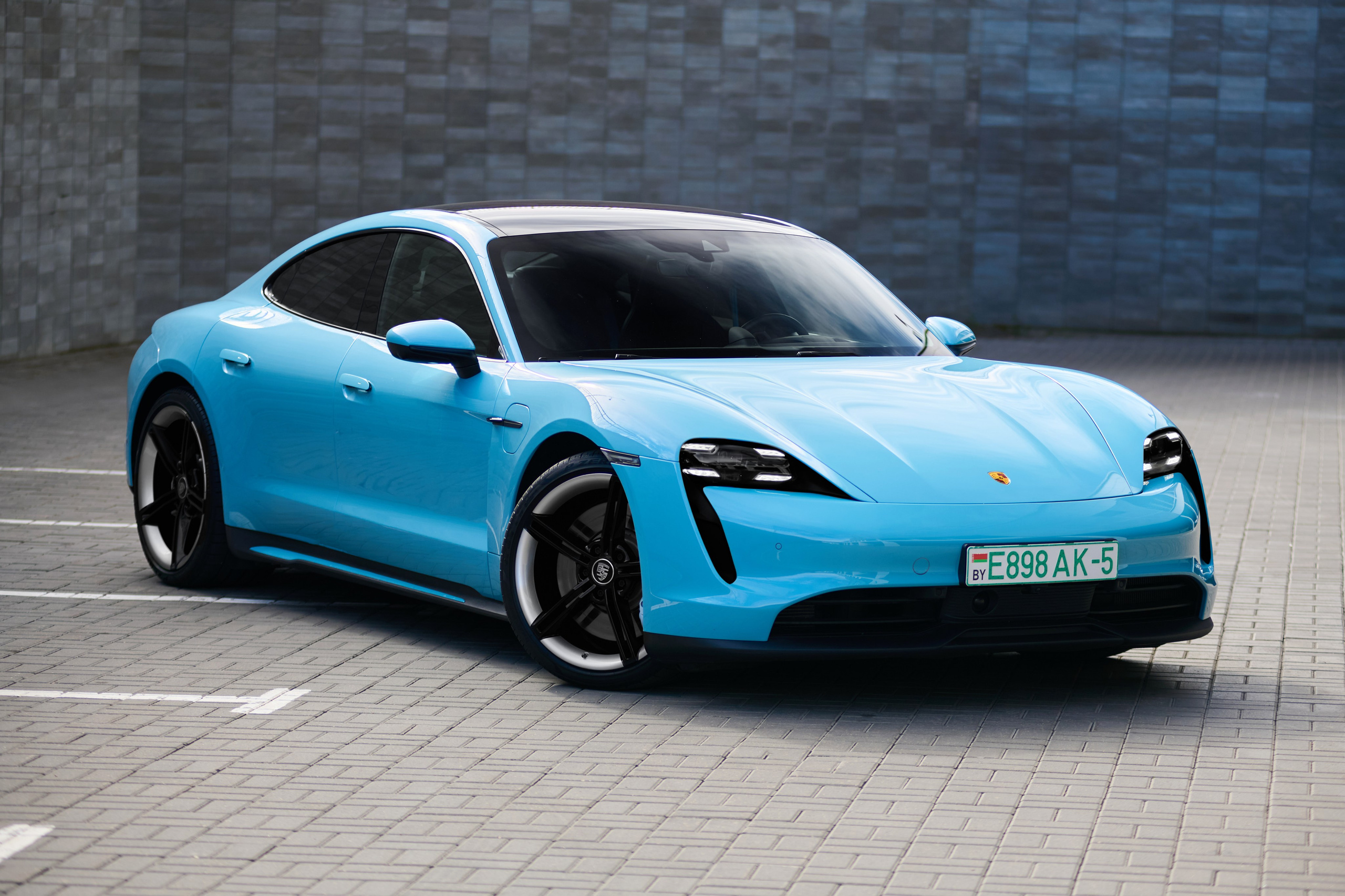 Голубой Porsche Taycan 4S с переднего правого ракурса на парковке