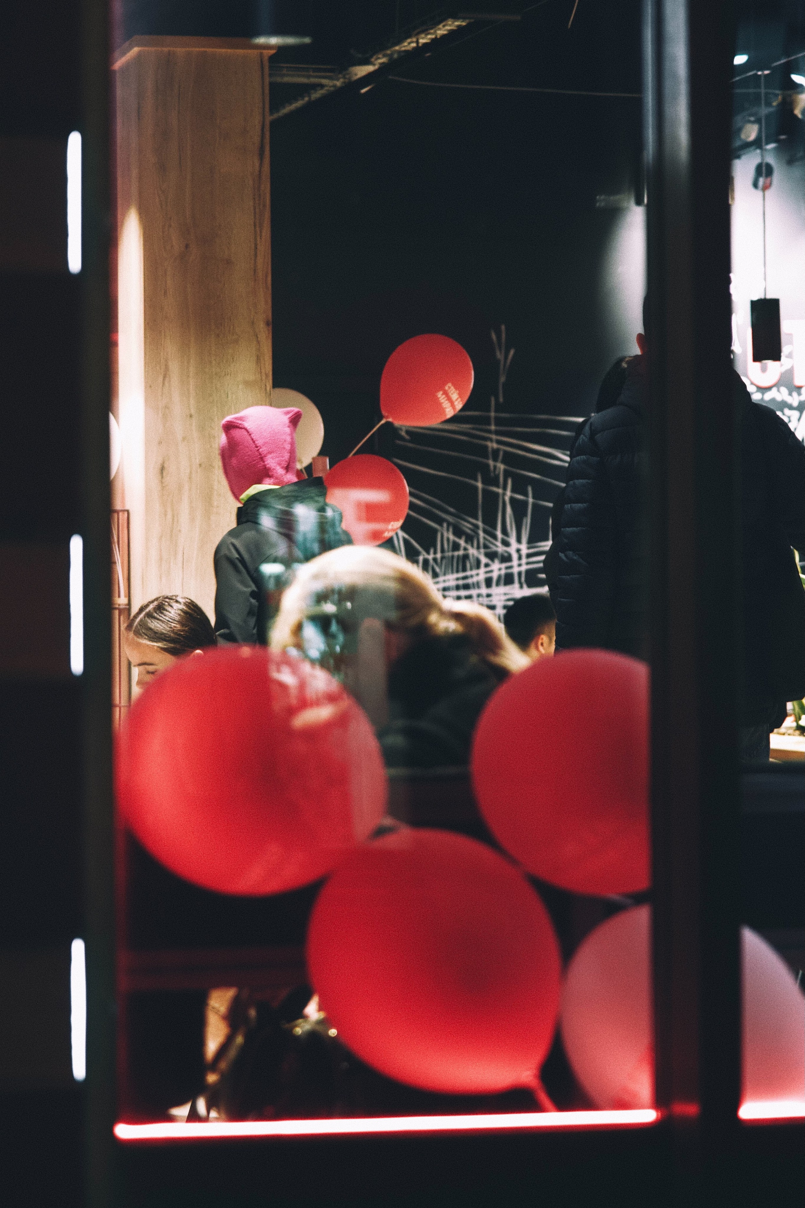 Витрина кафе с красными шариками и люди внутри