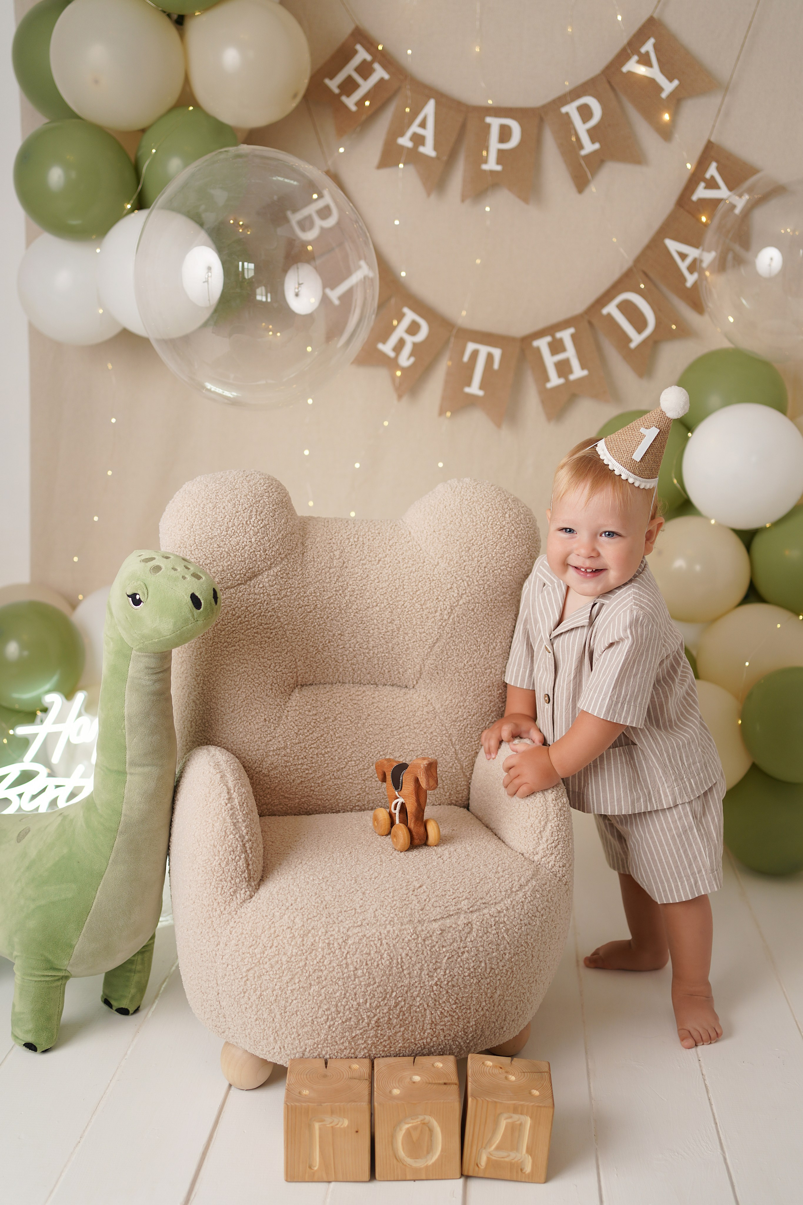 На фото малыш в праздничном колпачке С днем рождения, рядом кубики год, динозаврик.