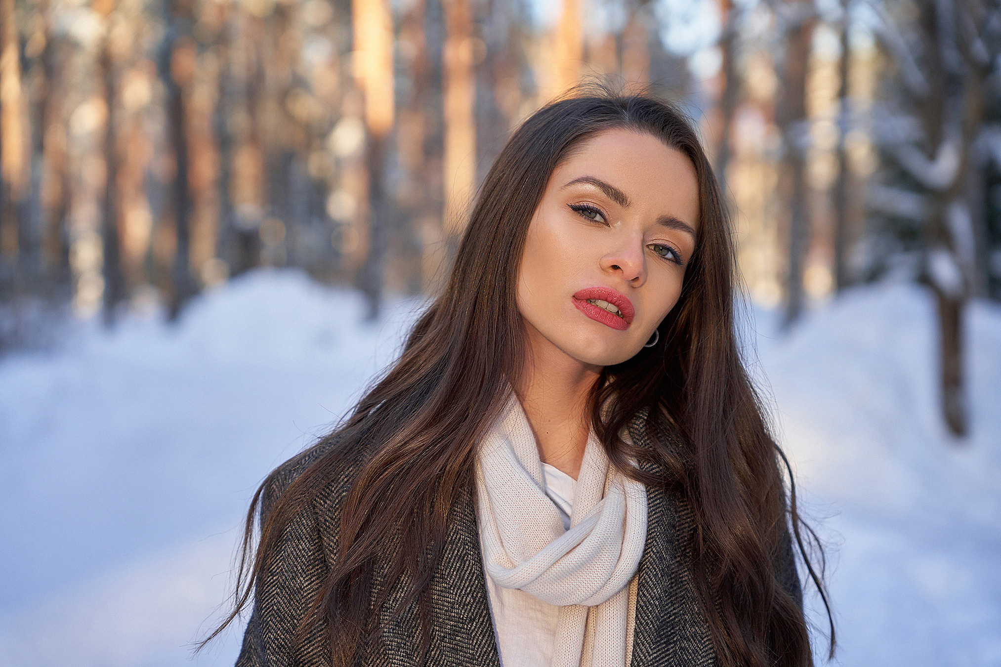 Портрет девушки в пальто в снежном лесу на закате