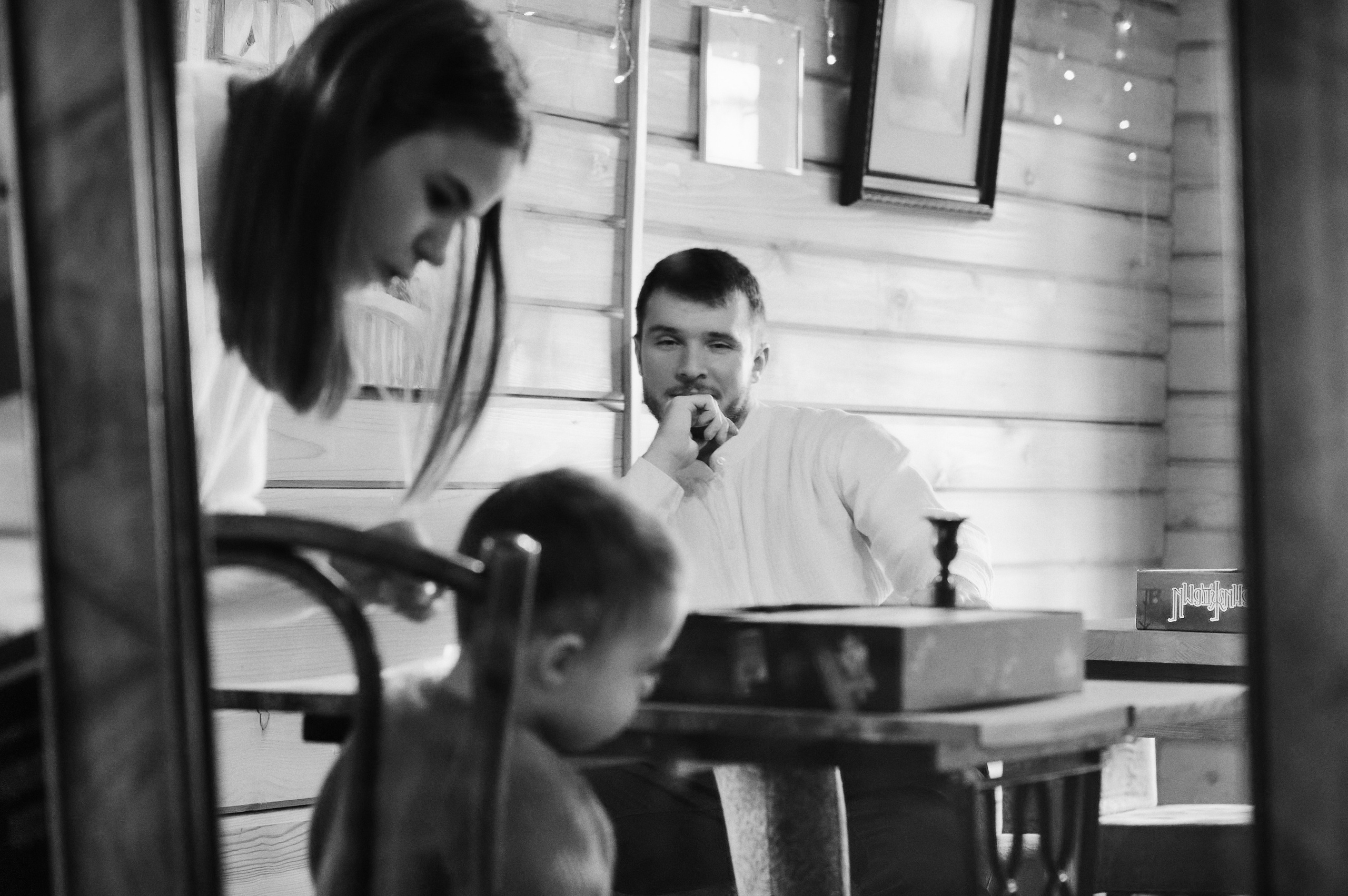 чёрно-белое фото: отец смотрит на сына, мама помогает у стола