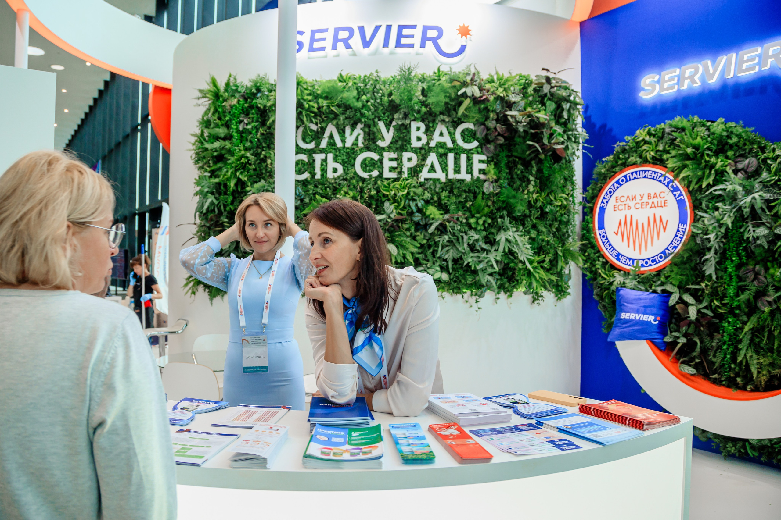 девушка за рекламной стойкой внимательно слушает гостя выставки