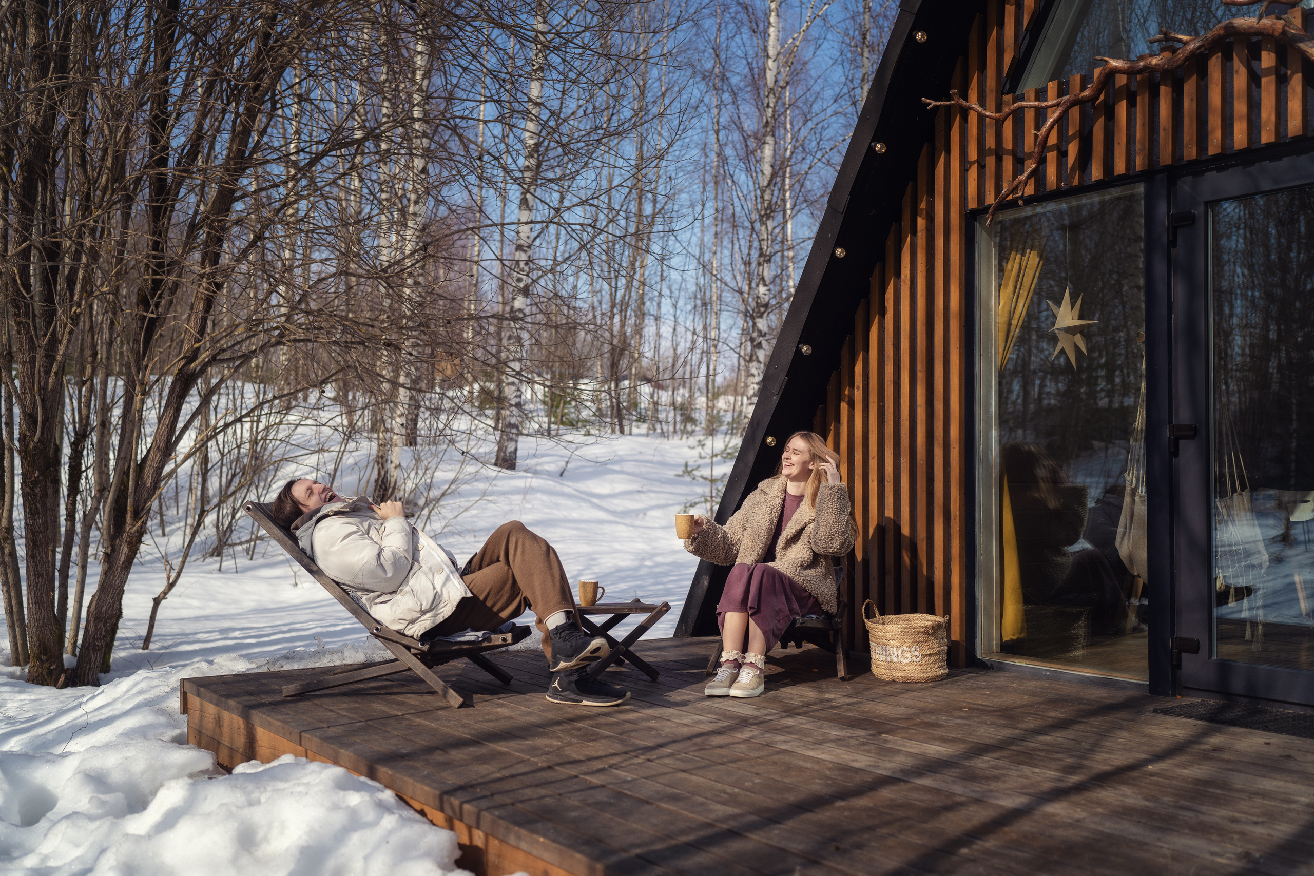 Влюбленная пара отдыхает в шезлонгах на террасе A-frame домика в глэмпинге