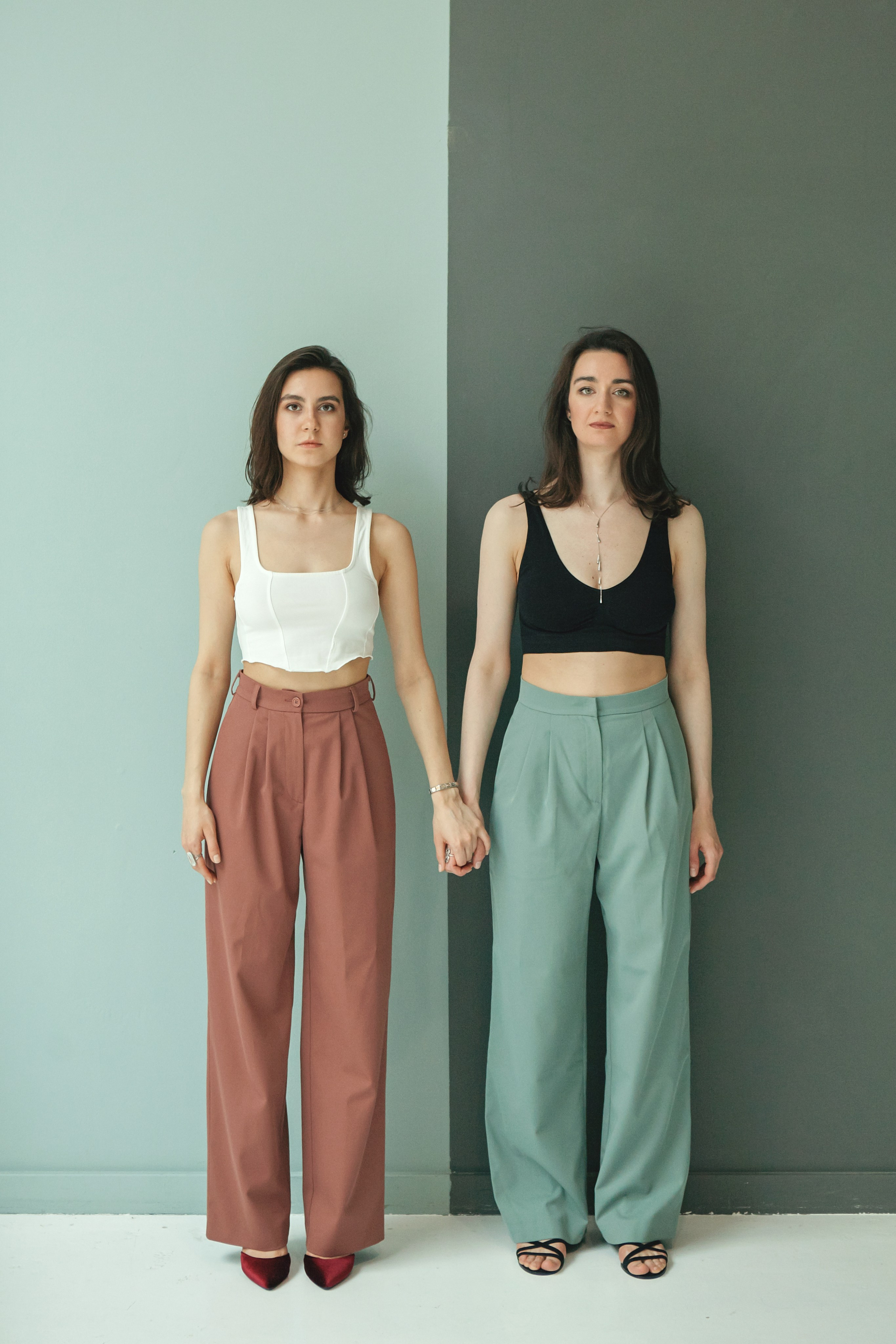 две сестры в одинаковой одежде держатся за руки