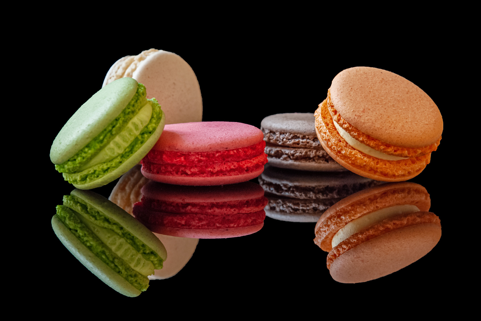 assorted macaroon cakes on a black mirroring surface