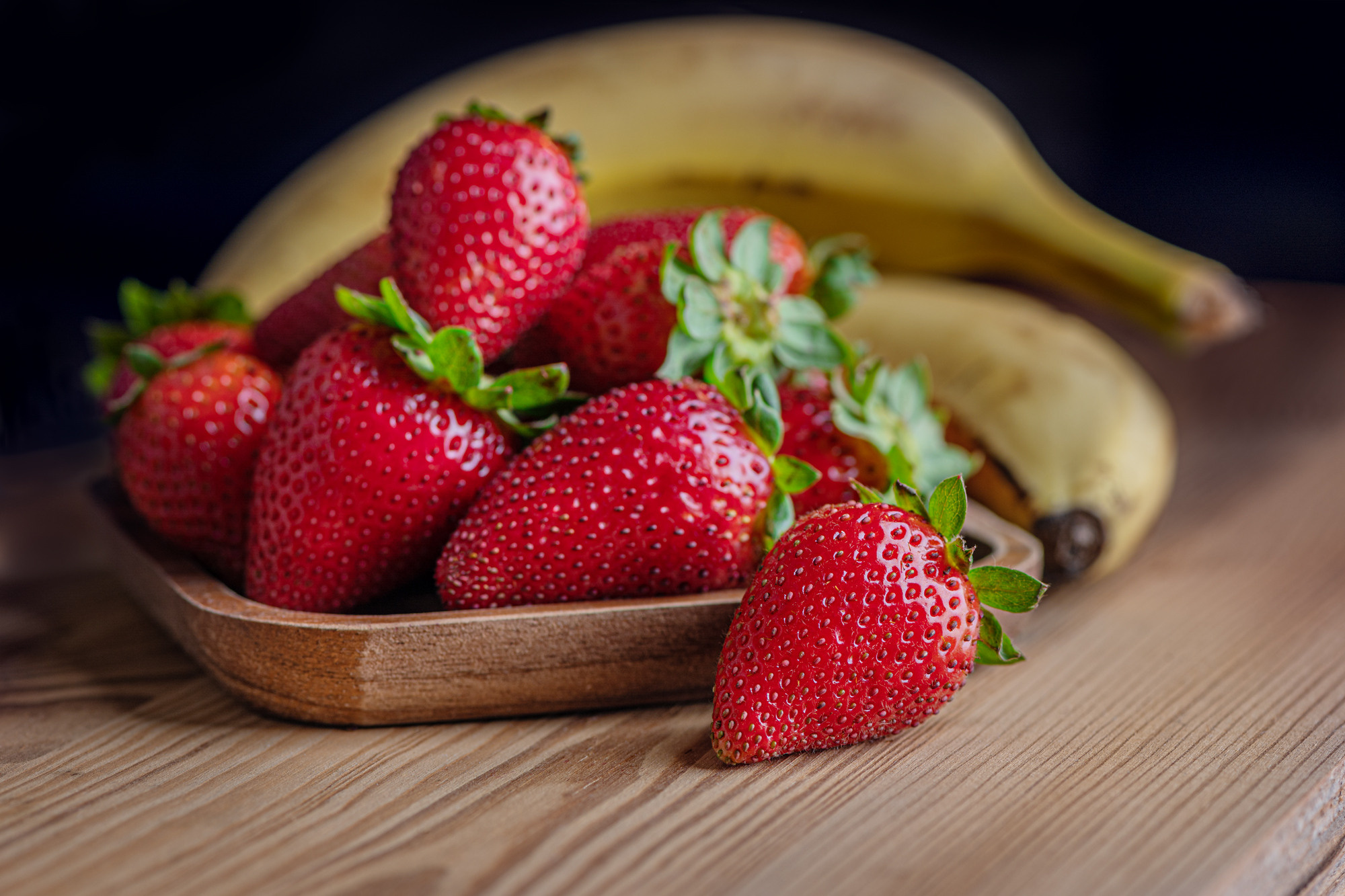 ripe juicy fragrant strawberries and bananas on an old wooden surface