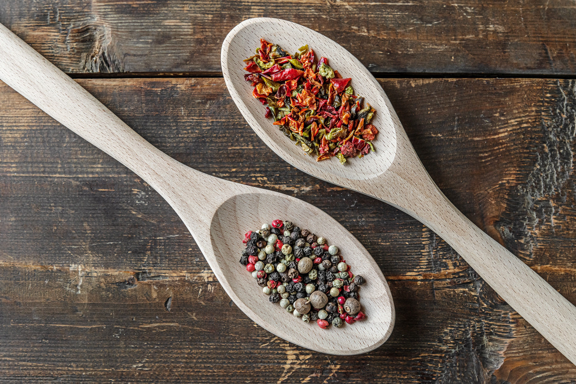 assorted peppers and paprika flakes on wooden spoons