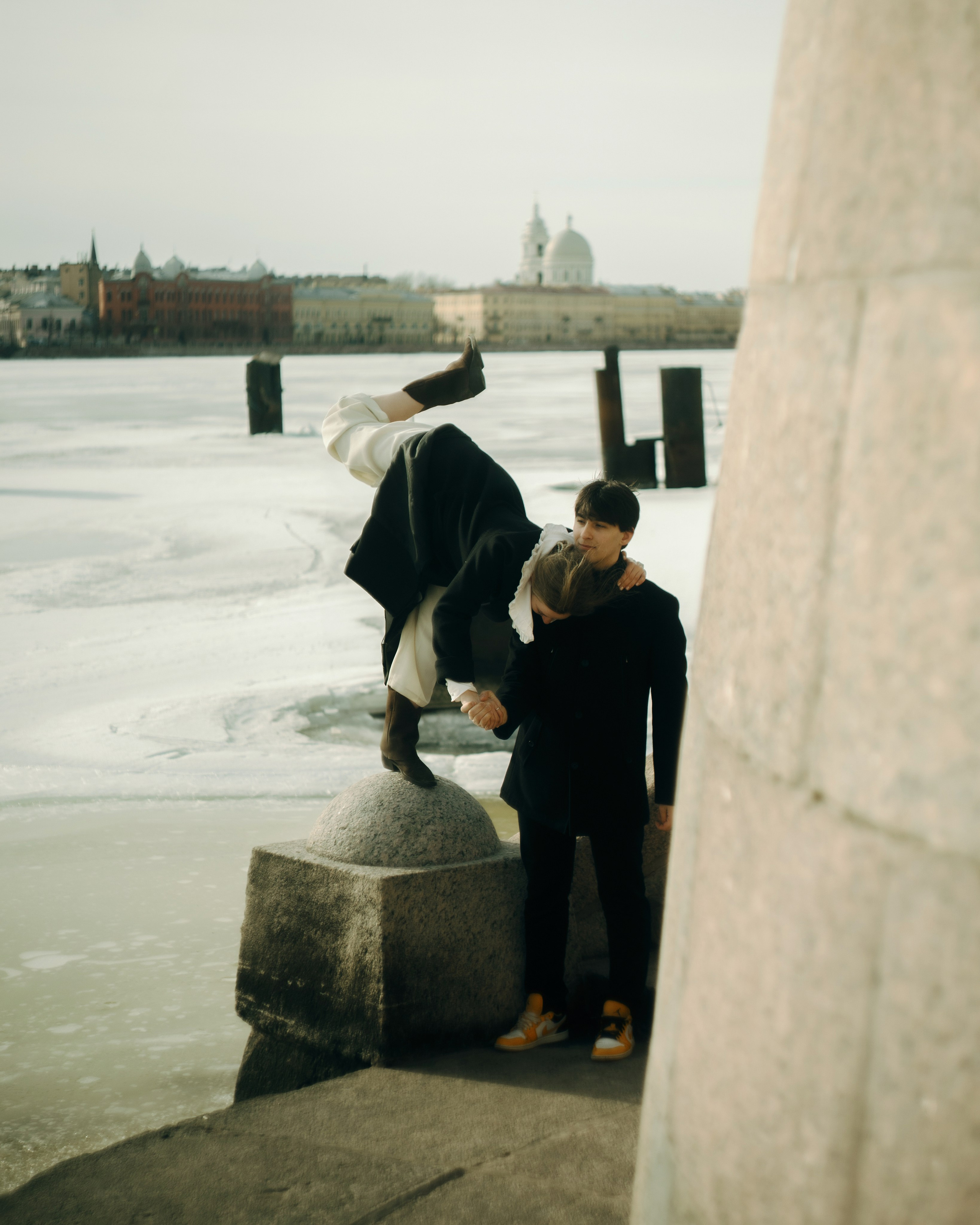 Фотосессия пары у воды в Санкт-Петербурге, девушка делает пластичный акцент на гранитной набережной, авторская love story съемка с нестандартными позами