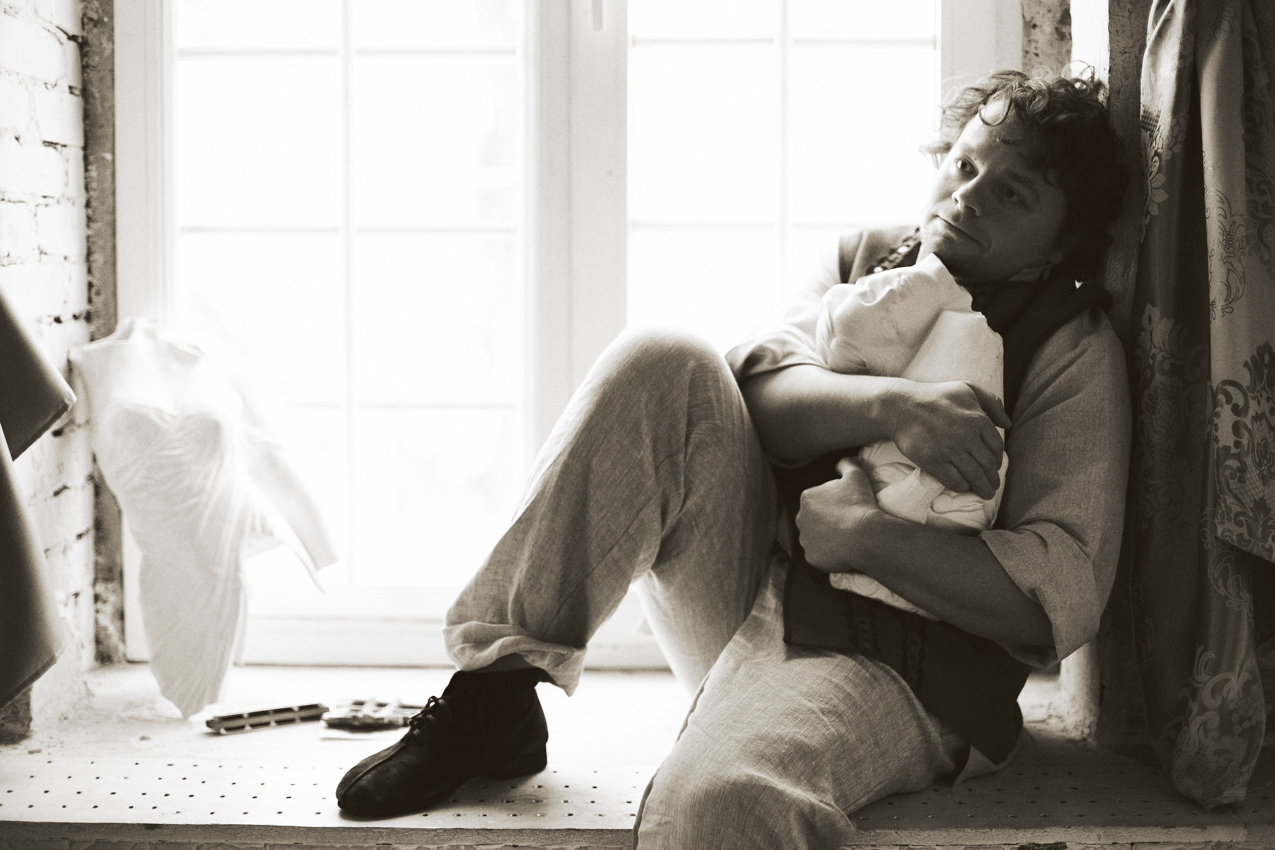 Черно-белый портрет актёра Сергея Друзьяка, сидящего на подоконнике со статуей в руках