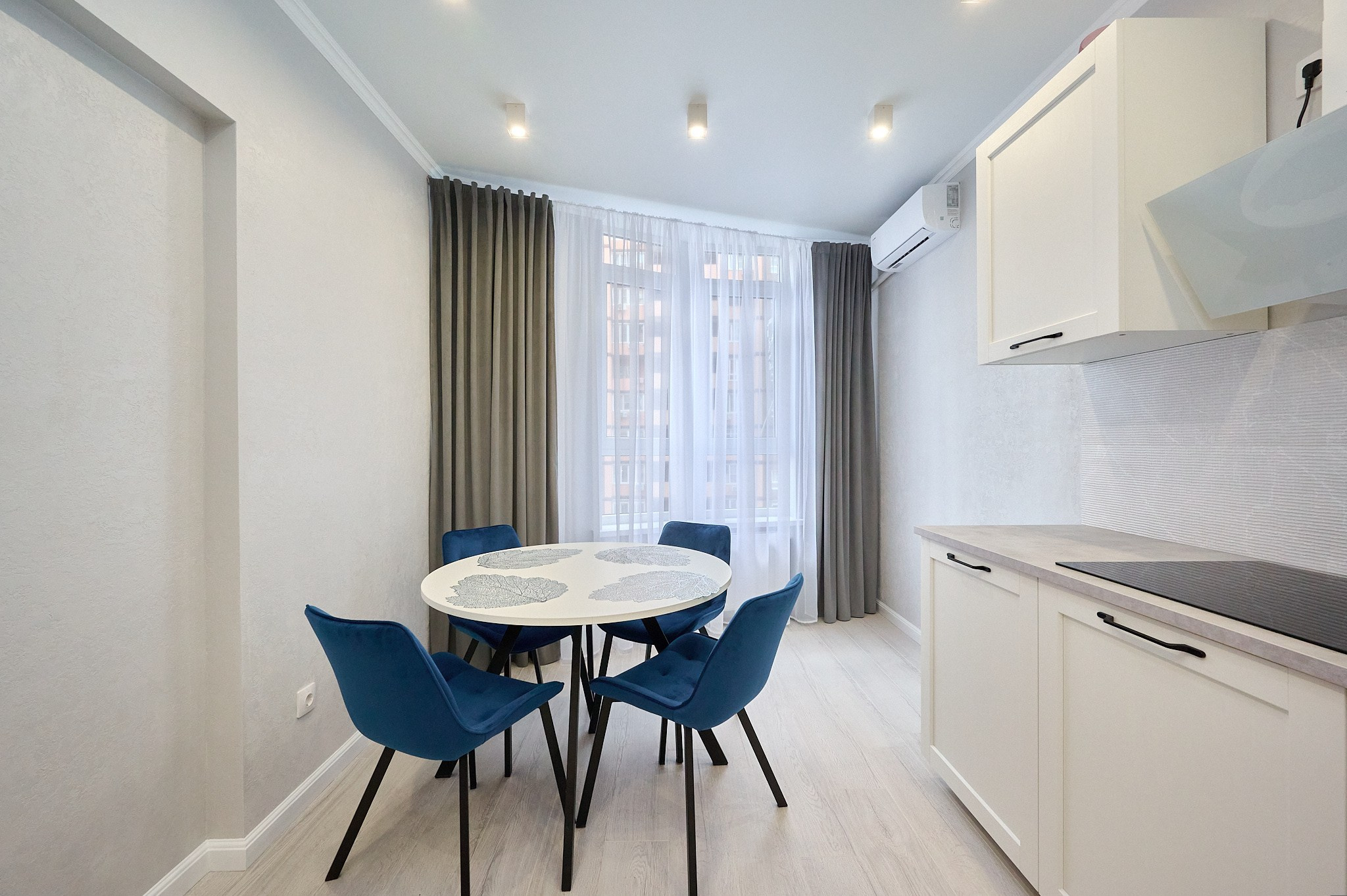 кухня светлые оттенки белые ящики и полки светлые шторы круглый стол синие стулья